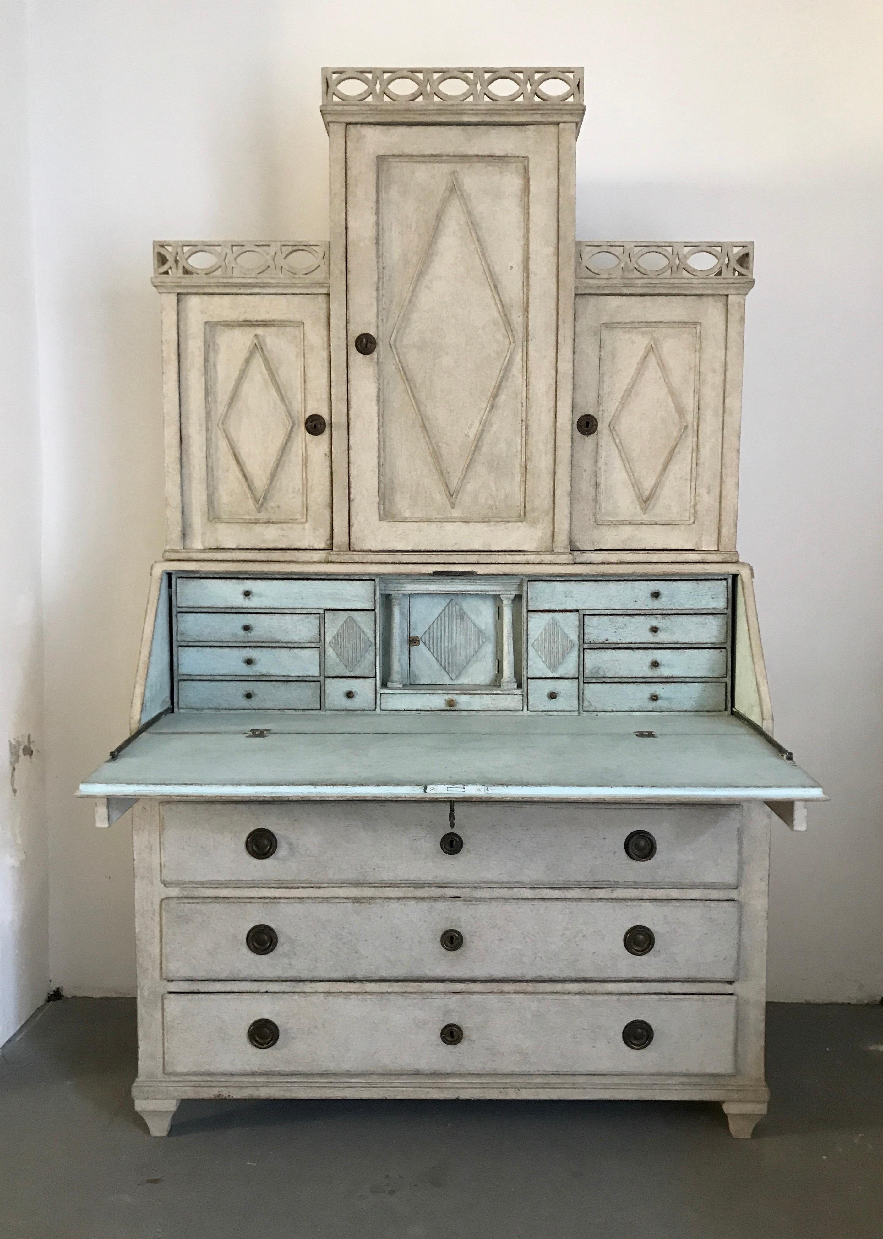 This beautiful Swedish secretaire contains 4 drawers and three doors. It features delicate decorations in the upper part and diamonds on the front of the door. In the central part there is a desk with 13 small drawers inside. The interior is