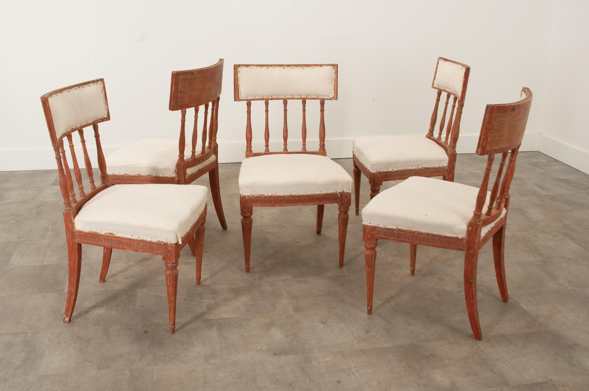 A set of five Gustavian style dining chairs, circa 1810, with fantastic potential in any space. The curved back rests feature reeding details on the back and seem suspended by turned spindles. Lambs tongue carving on the apron is interrupted by