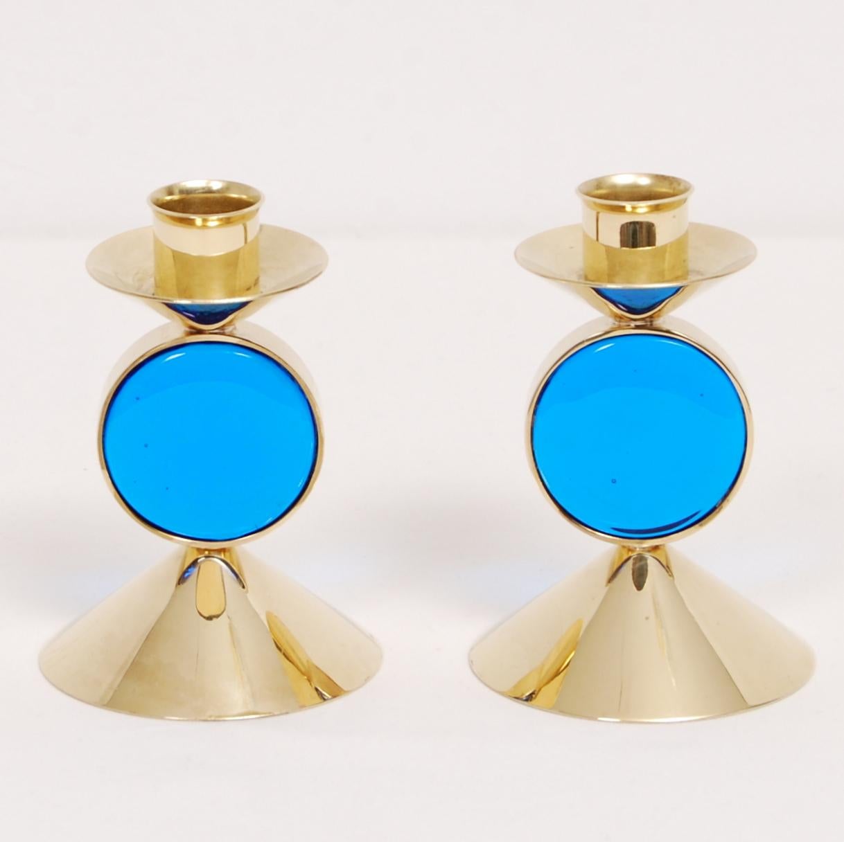A set of two Gunnar Ander candle holders in brass with mounted blue art-glass. Manufactured by Ystad Metall. Stamped and signed.
 