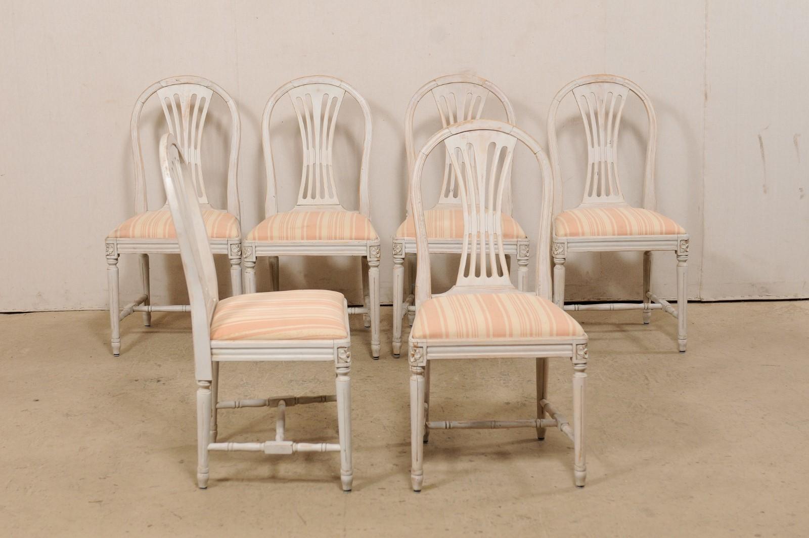 Schwedischer Satz von sechs geschnitzten Holzstühlen mit gepolsterten Sitzen, ca. 1960er Jahre. Dieses Set von Vintage-Stühlen aus Schweden zeichnet sich durch anmutig runde Stuhllehnen mit durchbrochenen Rückenlehnen aus, durch geformte Schürzen