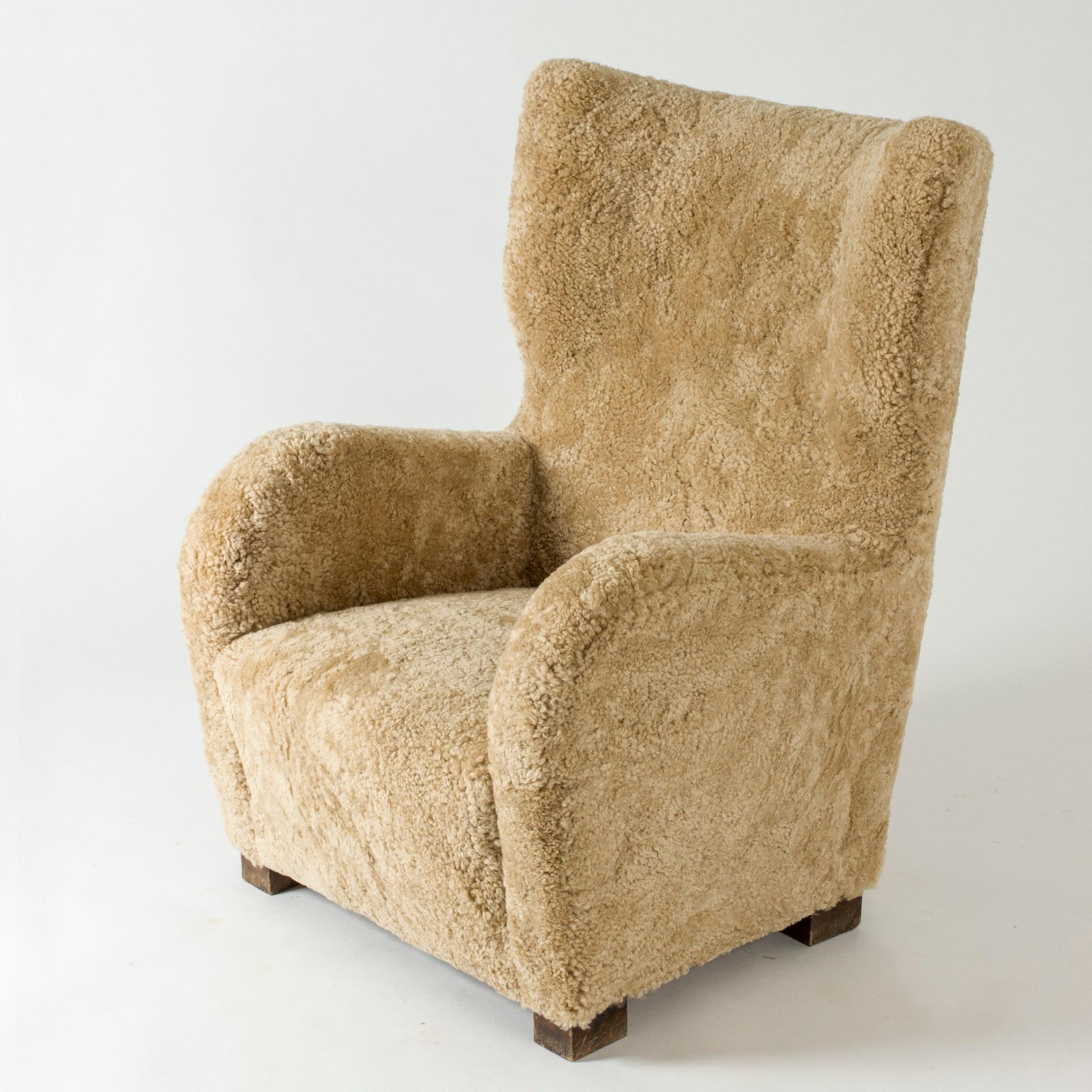 Amazing Swedish 1930s lounge chair in an oversized design with clean lines. Rembourré avec de la peau de mouton dans une nuance chaude, renforçant l'aspect accueillant de la chaise.
