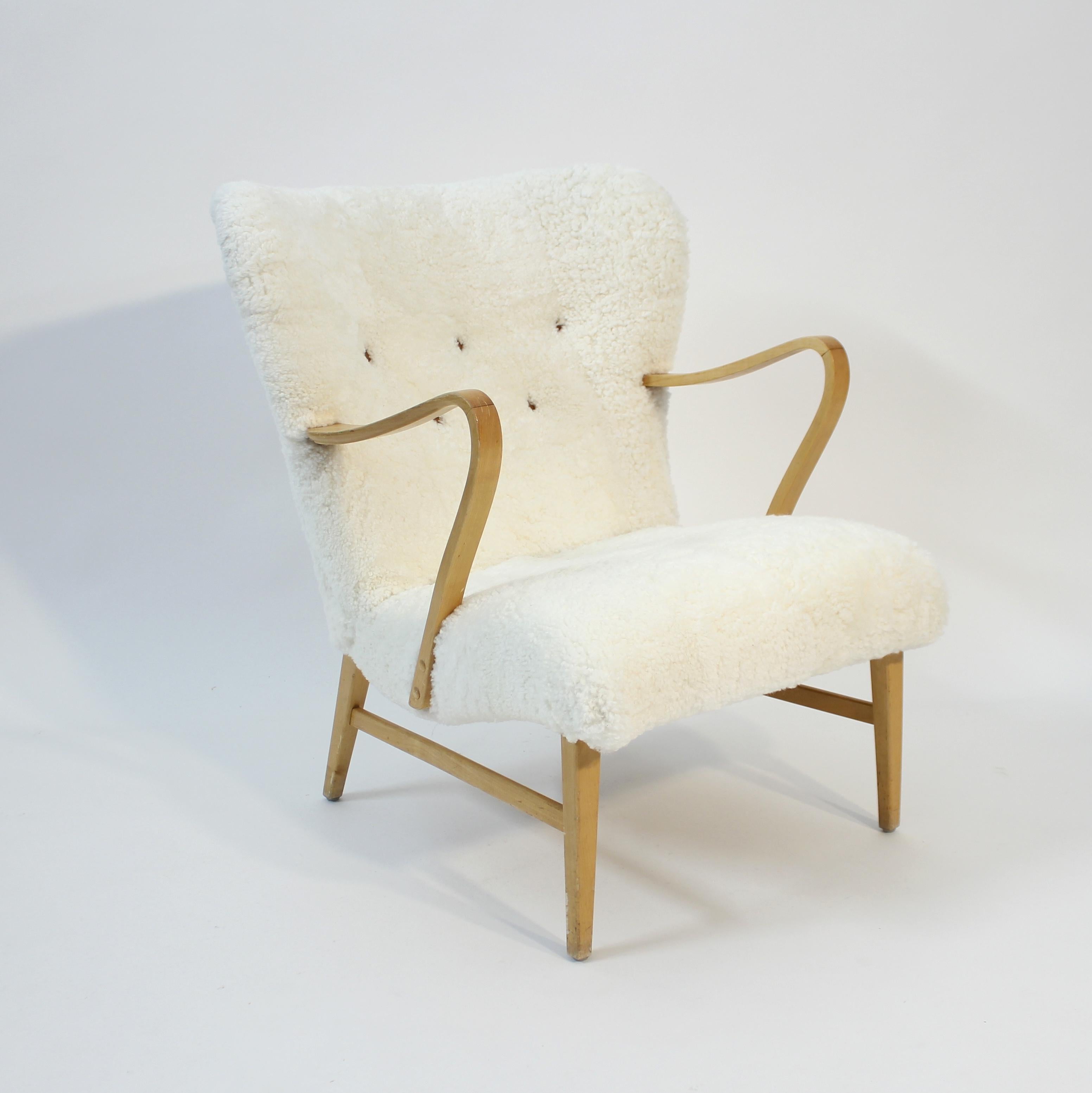 Poltrona moderna svedese della metà del secolo scorso, attribuita a Erik Bertil Karlén negli anni Quaranta. Nuova tappezzeria in pelle di pecora con bottoni in pelle marrone sul retro. Gambe e braccioli in betulla. La sedia ha un'espressione molto