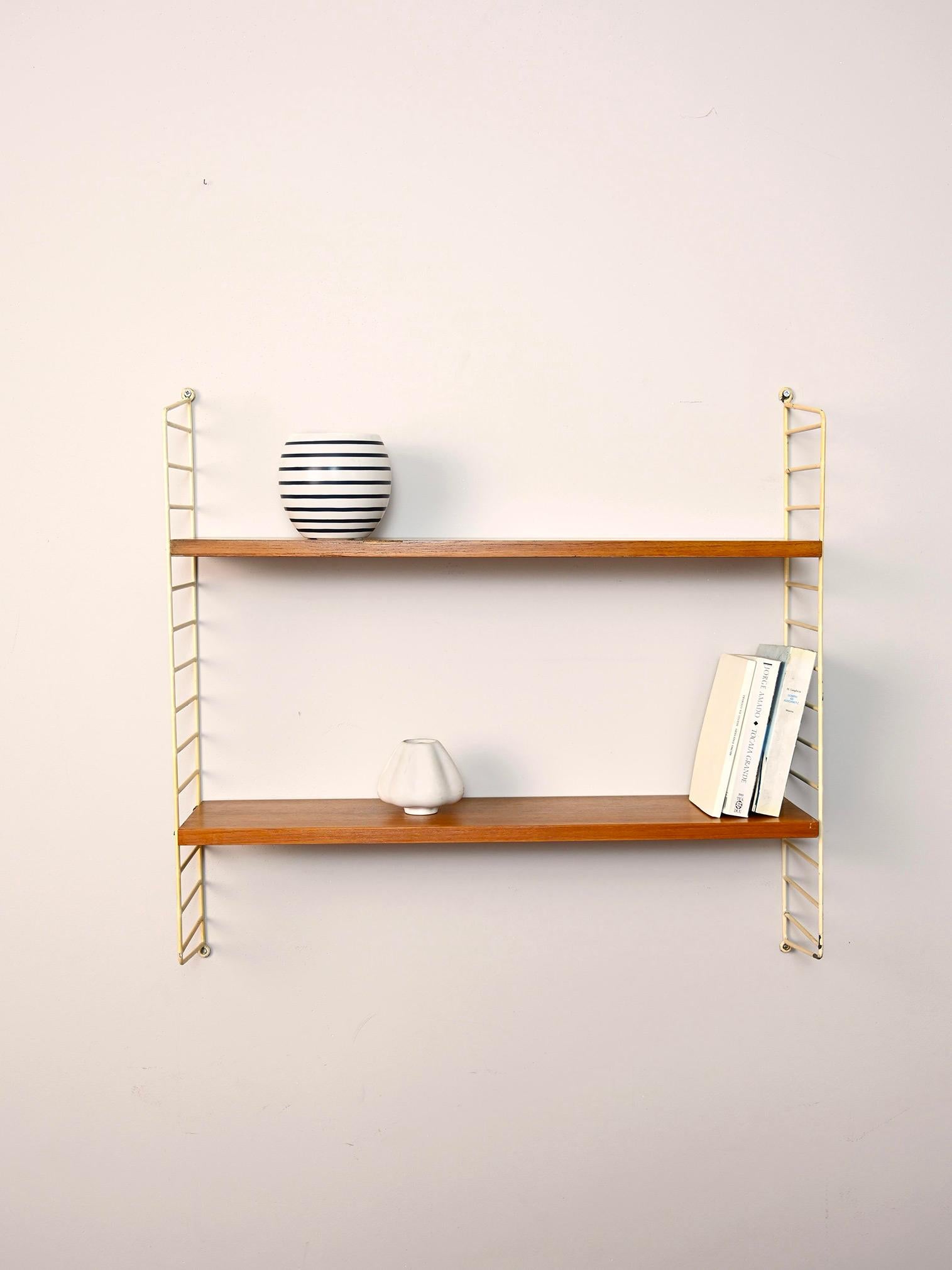 Original Scandinavian shelves from the 1960s.

This simple shelving system consists of a coated metal side frame to which two teak shelves fit.
Simple and functional it can be hung in different rooms of the house.

Good condition. It has been