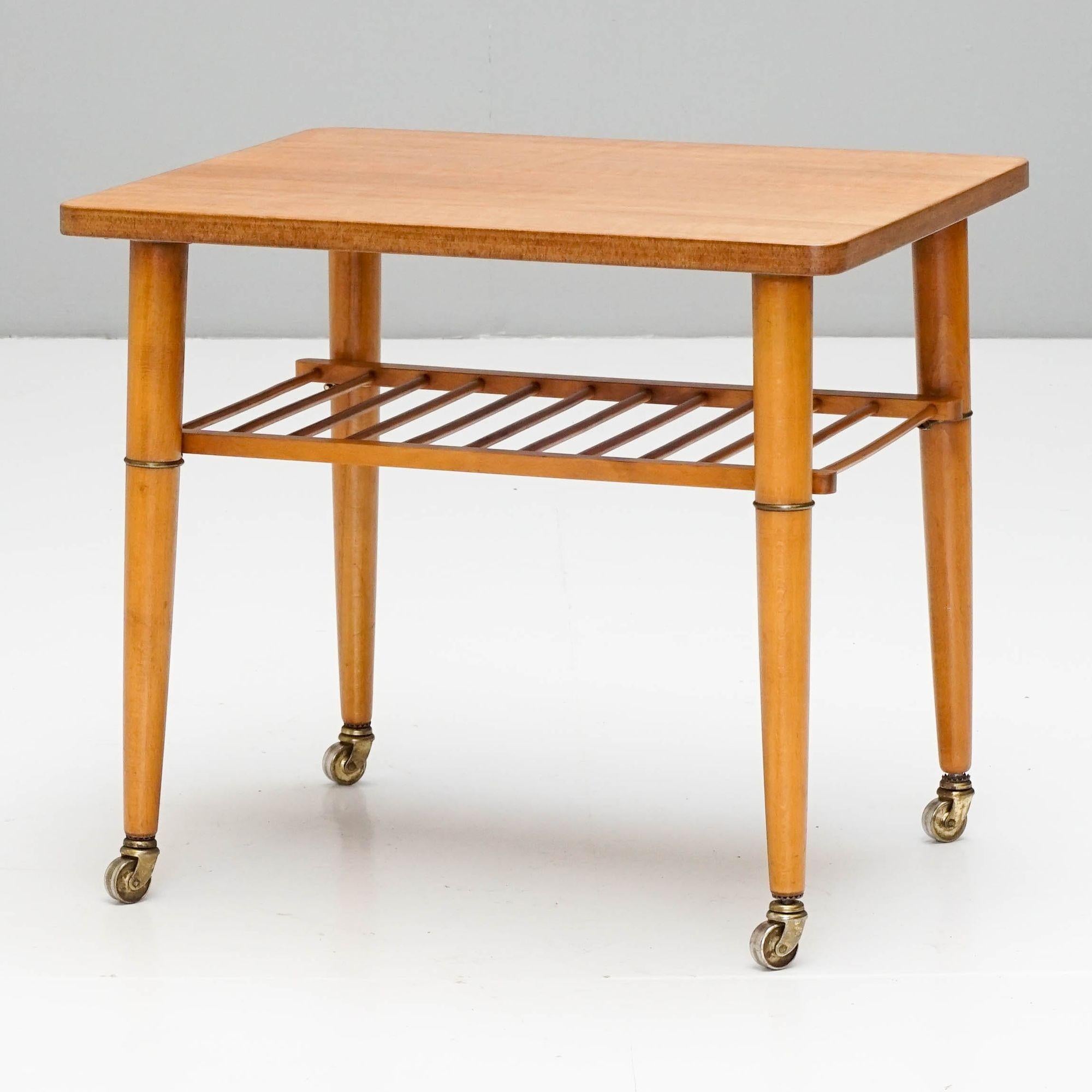 Useful occasional table on original castors with beech legs and magazine rack, teak veneered top.