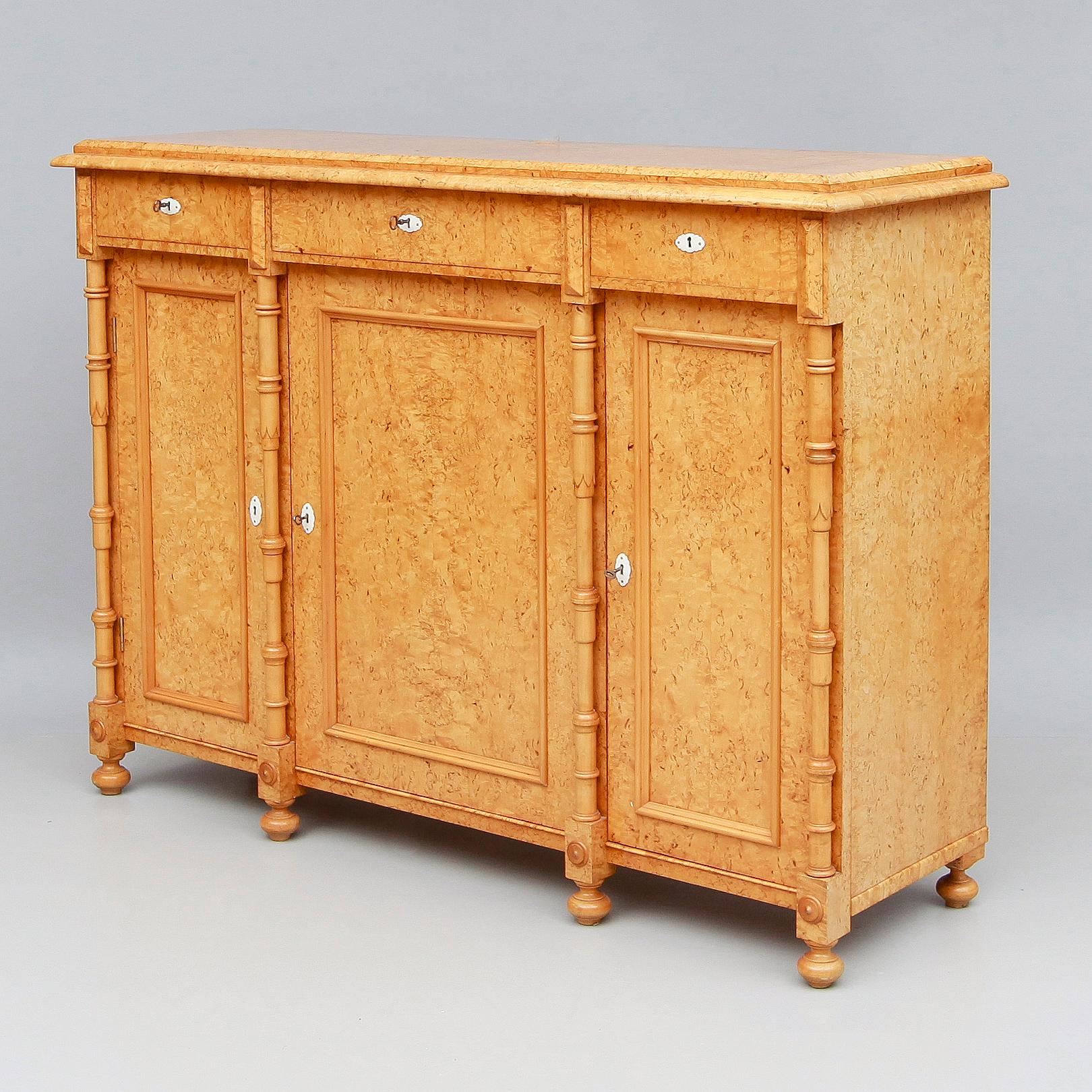 Swedish sideboard or storage cabinet, circa 1880. Completely rendered in highly figured golden birch root (Karelian birch). Key surrounds are original. Columns in solid birchwood. With three drawers and three storage cabinets. Some stains inside of