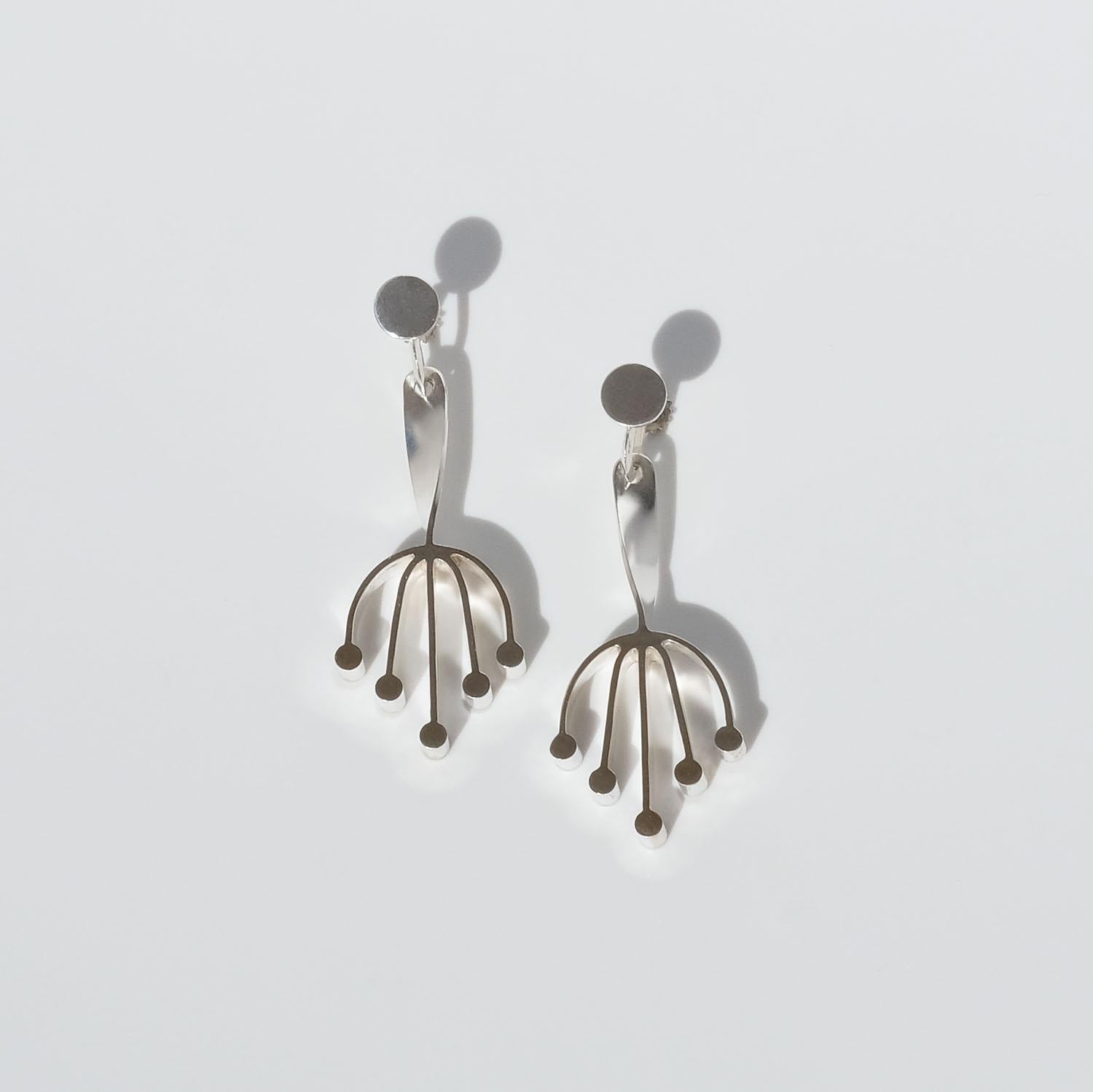 These silver earrings have a matte surface and gilded fronts, and with that they convey a certain elegance, but since the shape of the earrings is similar to a fairy tale toad foot, they also have a playful look. The shafts of the earrings are