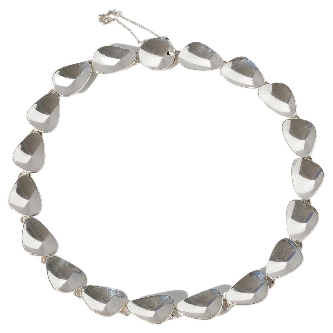 Diese silberne Halskette hat eine glänzende Oberfläche. Die kleinen Silberplättchen sind als perfekte Silbermuscheln geformt und mit Silberringen miteinander verbunden. Die Halskette lässt sich mit einem Kastenverschluss leicht schließen und hat