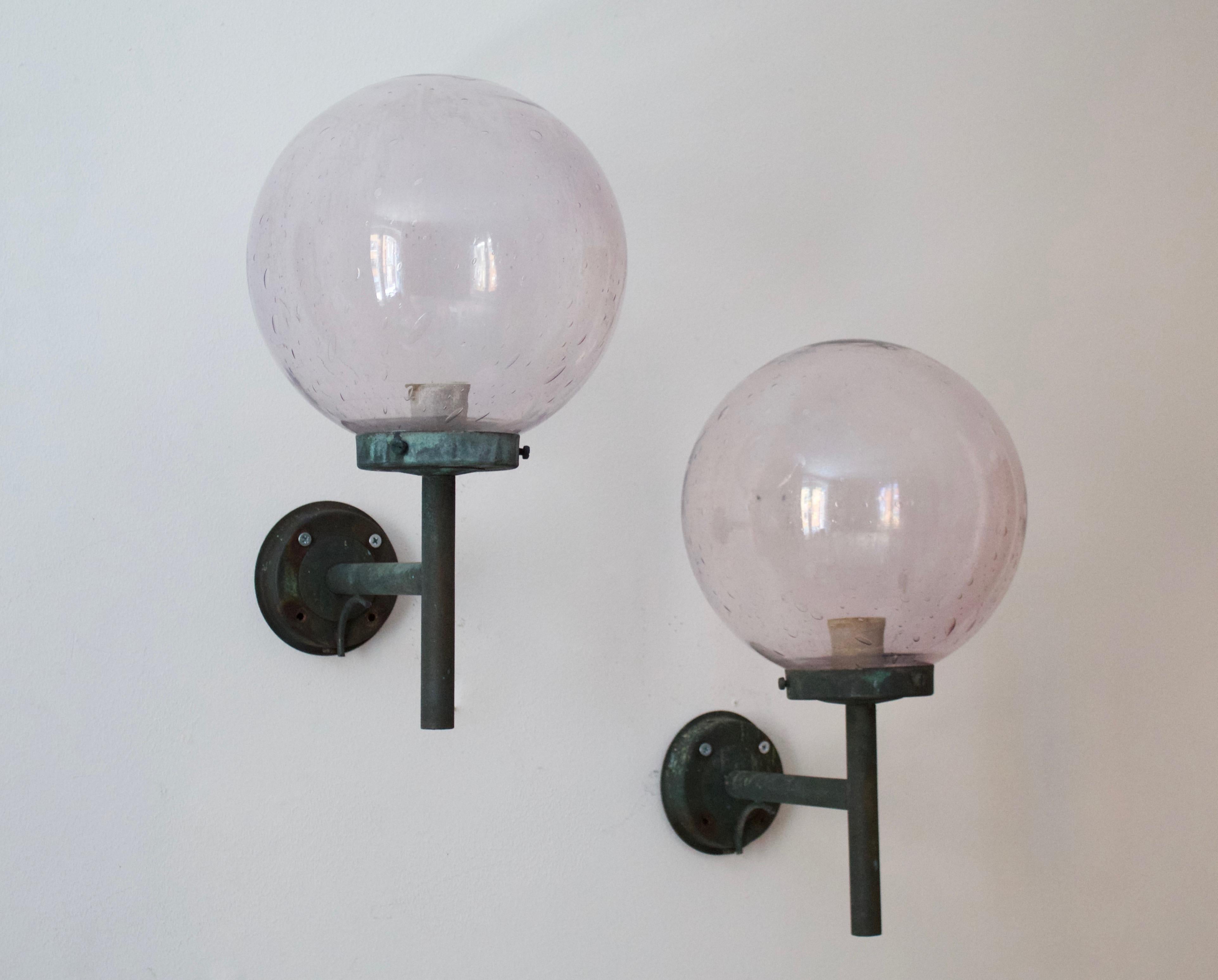 A pair of sizable wall lights. Designed and produced in Sweden, 1950s. Features patinated copper and blown glass shades with a light purple tint. 

 