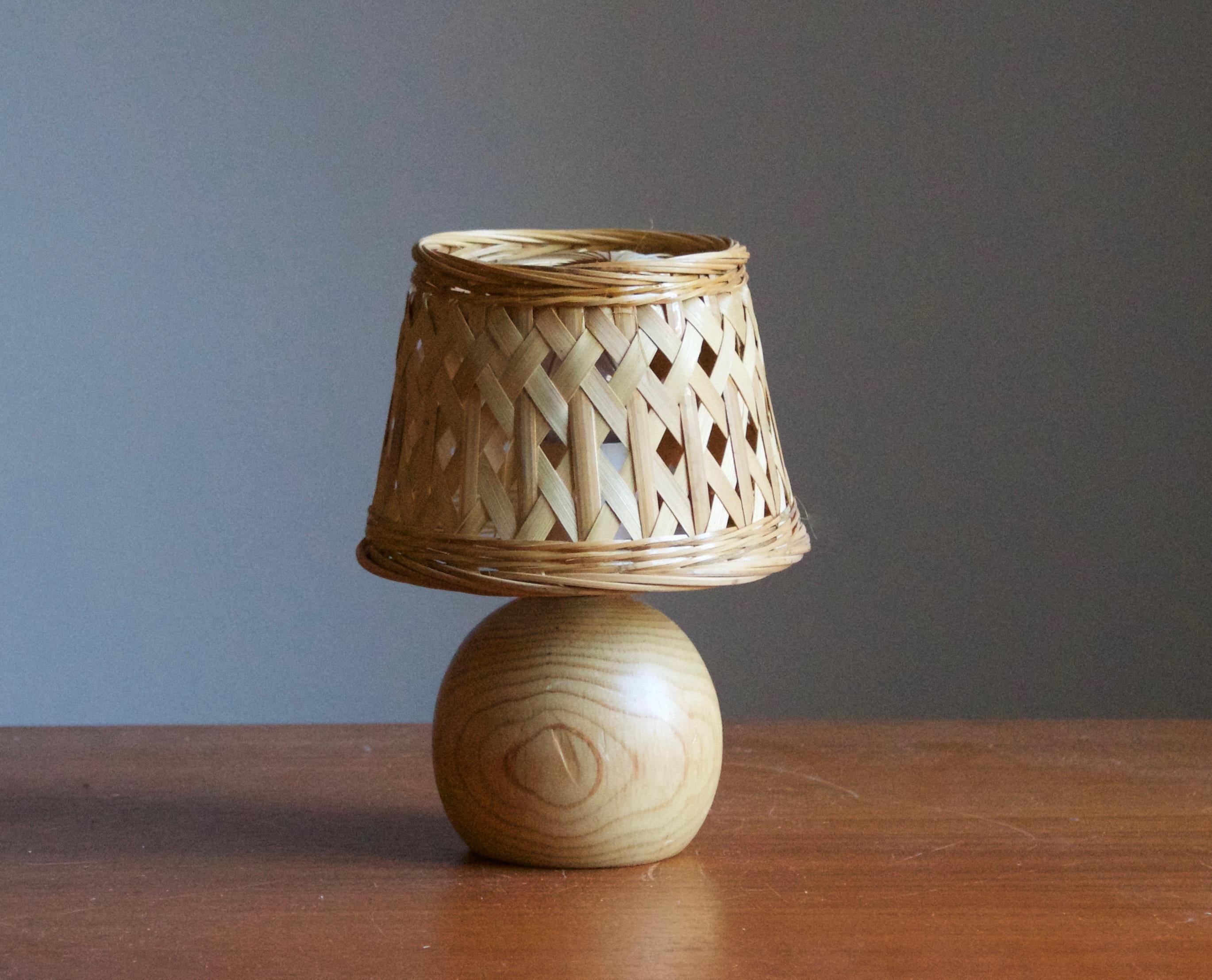 A pine table lamp, designed and produced in Sweden, c. 1970s. 

Stated dimensions exclude lampshade. Height includes socket. Upon request illustrated vintage rattan lampshade can be included.