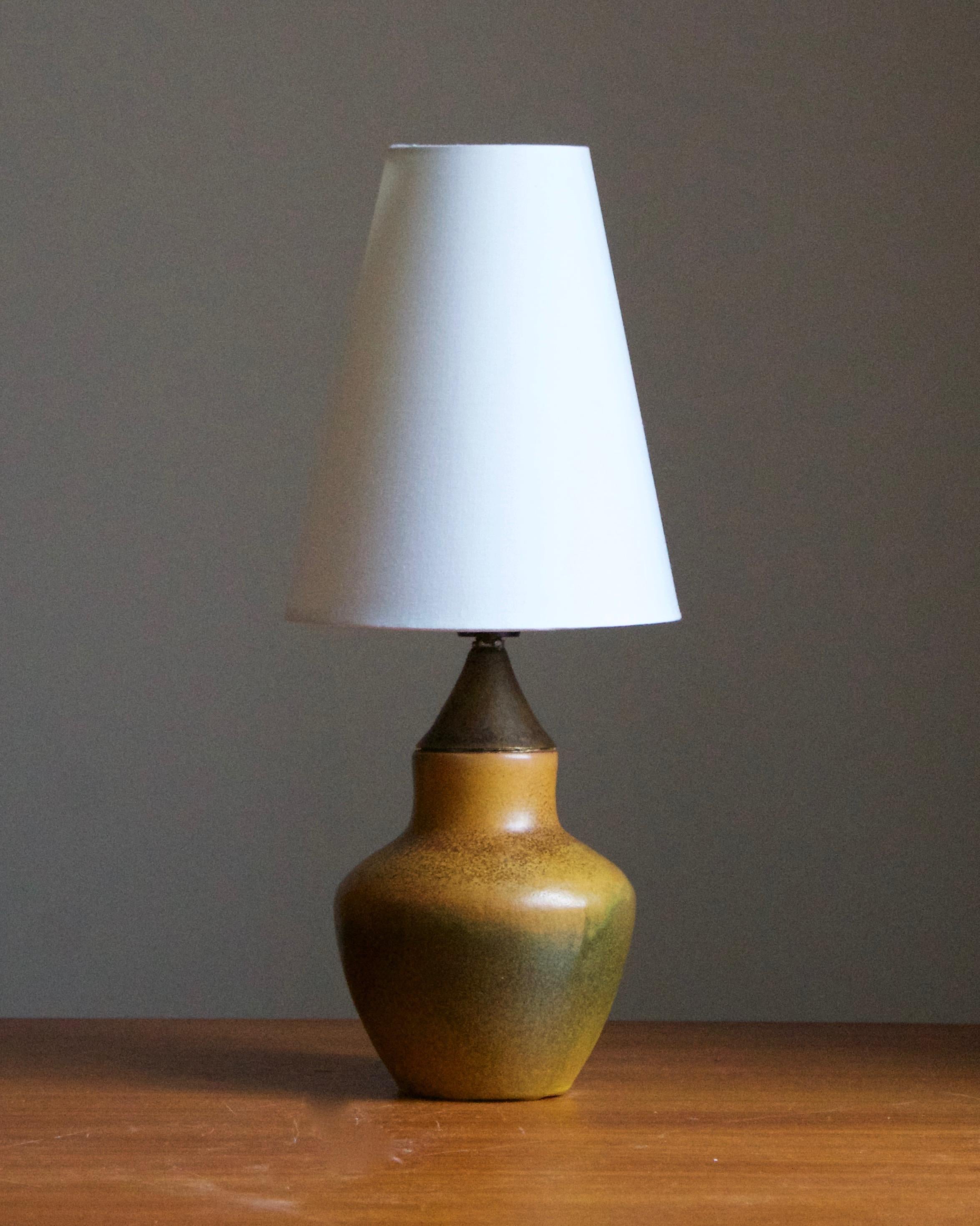 A small table lamp. Designed and produced in Sweden, 1940s. Brand new lampshade.

Glaze features orange-green-brown colors.