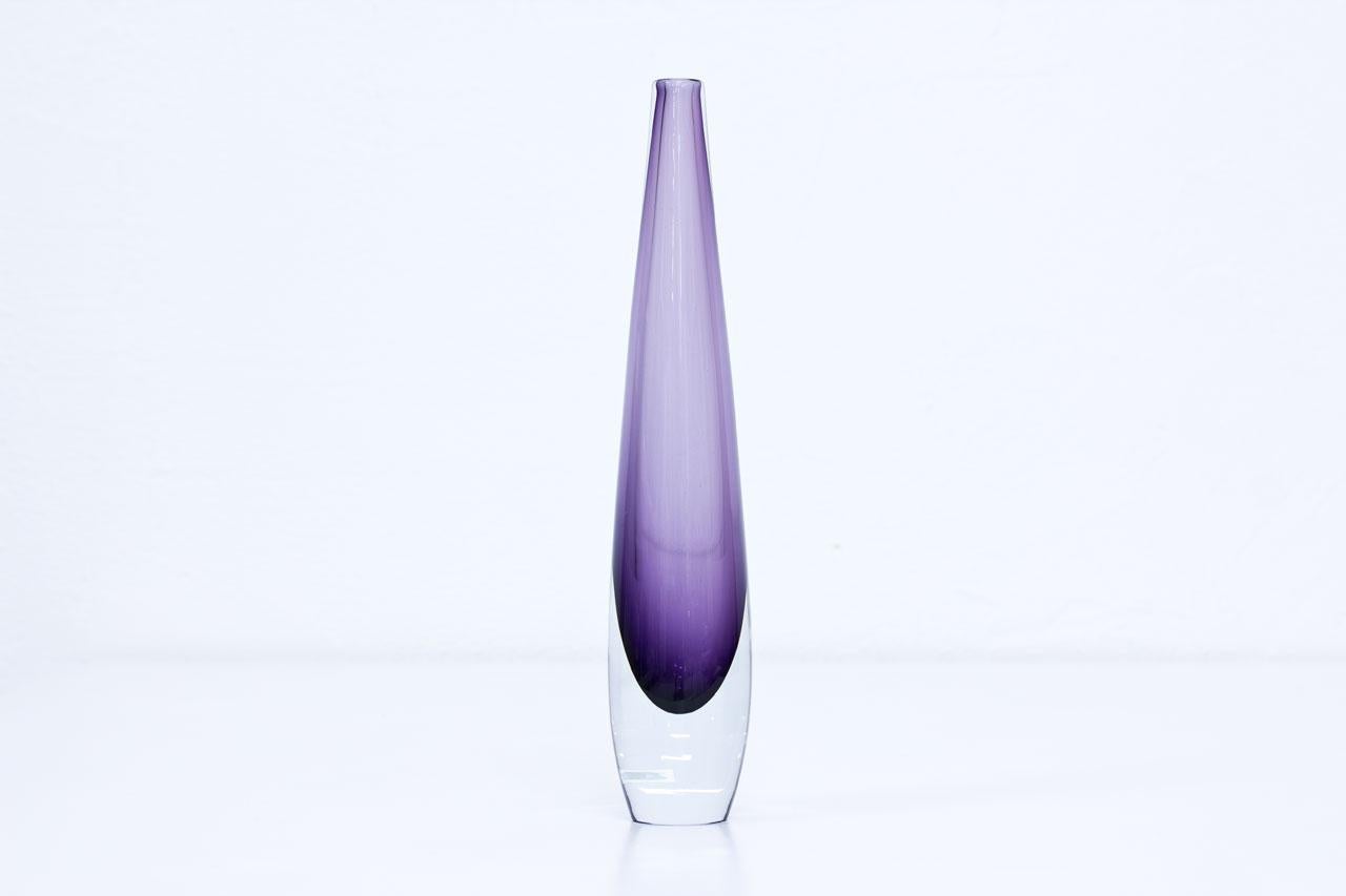 Tall flute vase designed by Asta Strömberg. Manufactured at Strömbergshyttan factory in Sweden during the 1950s. Purple color glass cased in clear. Labeled and engraved on bottom.