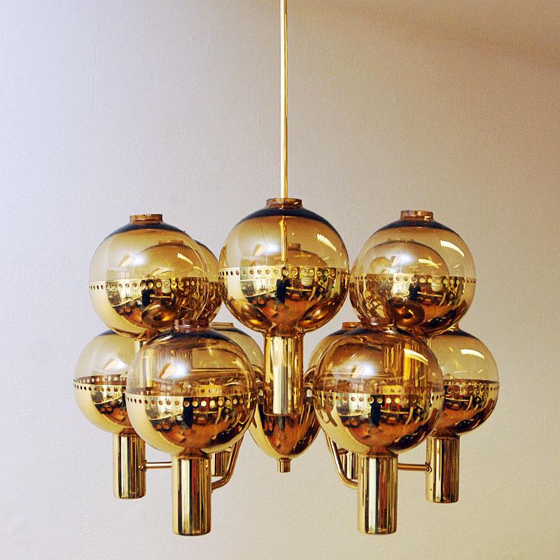 A fabulous and stunning special edition Patricia Chandelier model T372/12 by Hans-Agne Jakobsson for Markaryd AB, Sweden 1950s.
This is a 12-armed chandelier made of polished brass with gold colored glassdomes held up by brass cups all around. The
