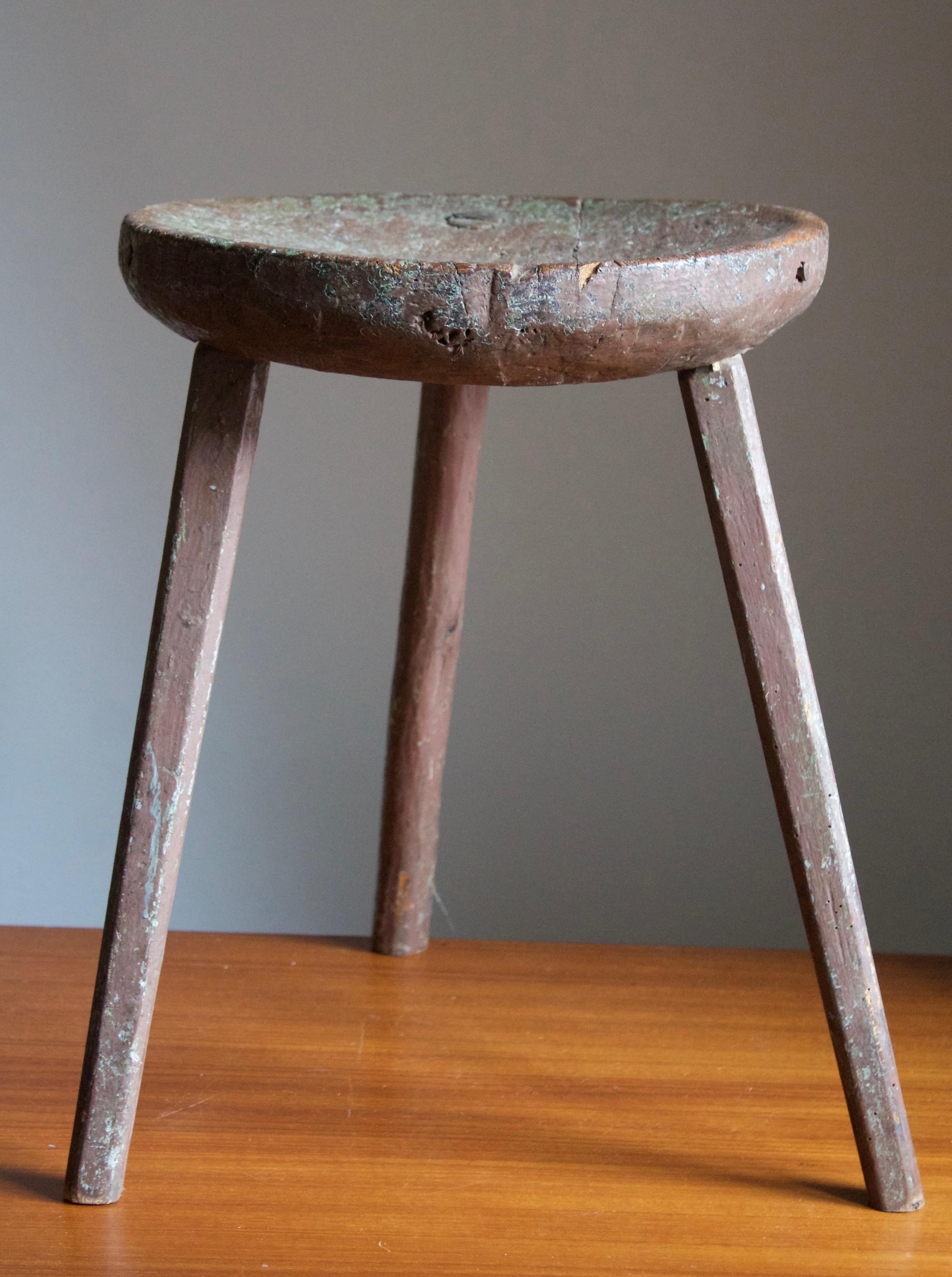 A carved stool. In brown-painted wood. Features carved wood and revealed joinery. In untouched original condition.