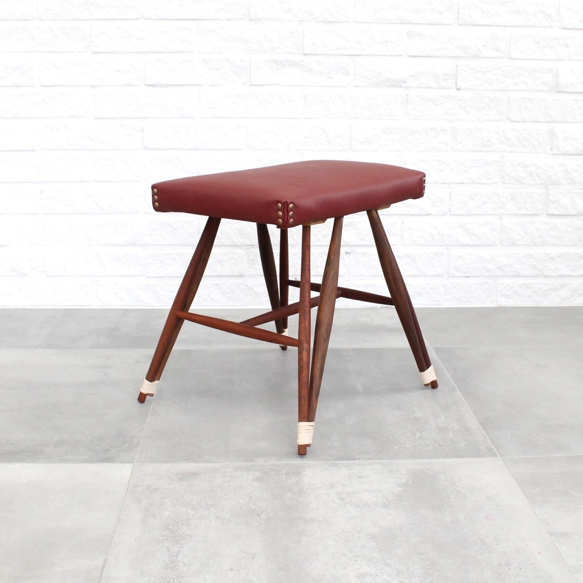 Ce tabouret suédois unique se caractérise par une construction en noyer massif, complétée par un revêtement en cuir rouge et des détails en rotin distinctifs autour des pieds. Notamment, sa silhouette caractéristique d'Eiffel est obtenue grâce à