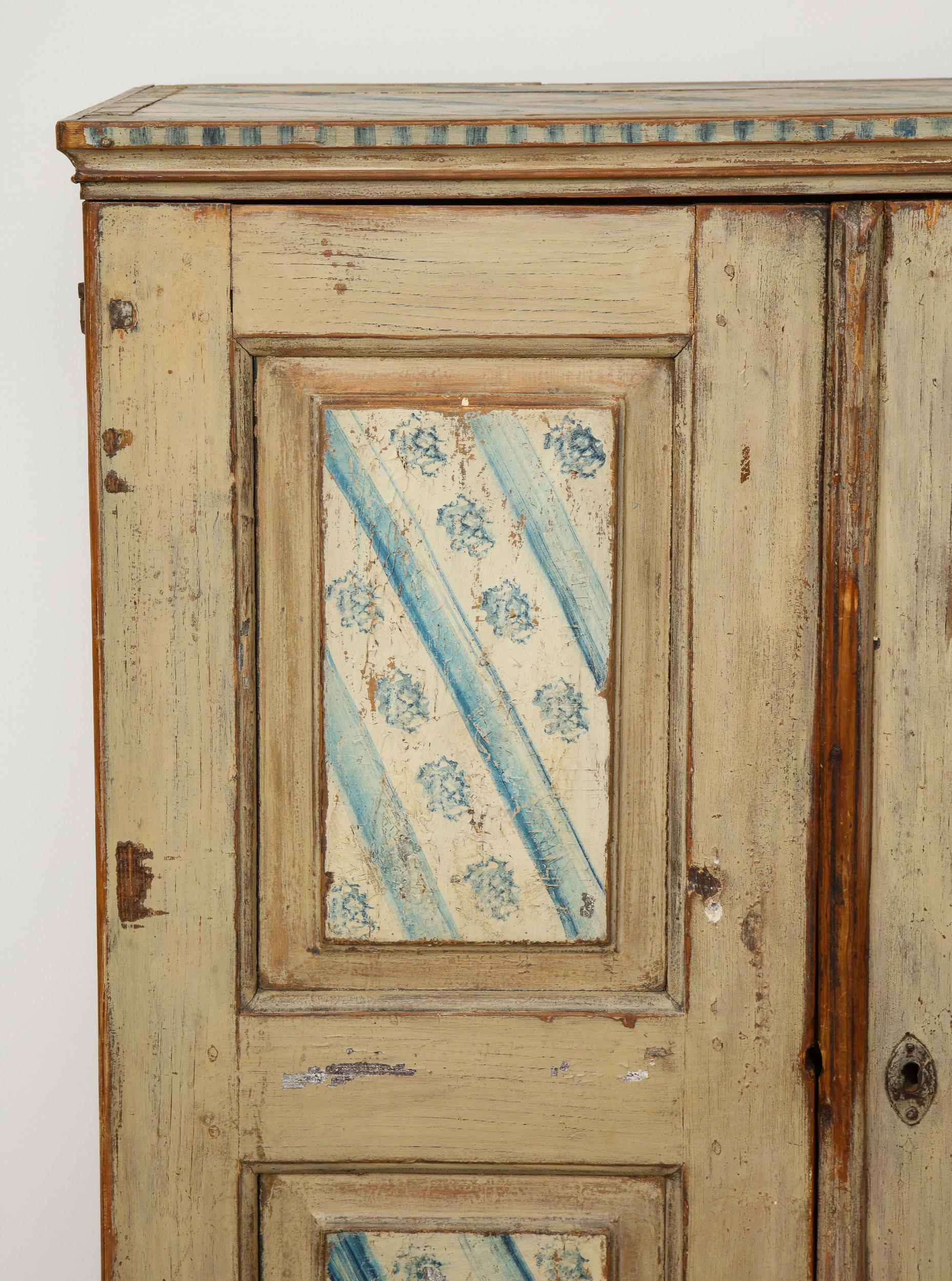 A late 18th-century Swedish Folk Art pinewood cabinet. The four-door panels have been sponge-painted and bookmatched, done in a blue and white stripe and floral pattern. The top of the cabinet is finished in the same painted pattern. A wonderful