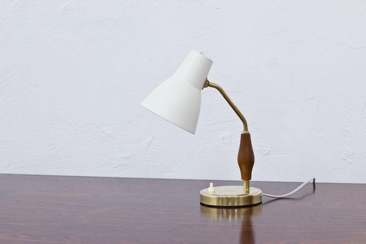 Clean desk/ table lamp designed by Hans Bergström, manufactured by ASEA in Sweden during the 1950s.
Off-white lacquered metal shade, polished brass base and sculpted teak handle. 
Rewired.