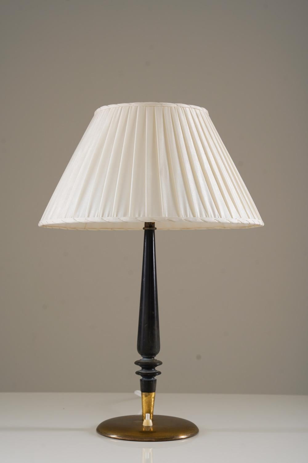 Table lamp model 30592 by Nordiska Kompaniet, Sweden, 1943.
This elegant lamp was manufactured during the Swedish Modern era and is of very high quality.
It consists of a brass base, supporting a black wooden rod holding the light source, hidden by