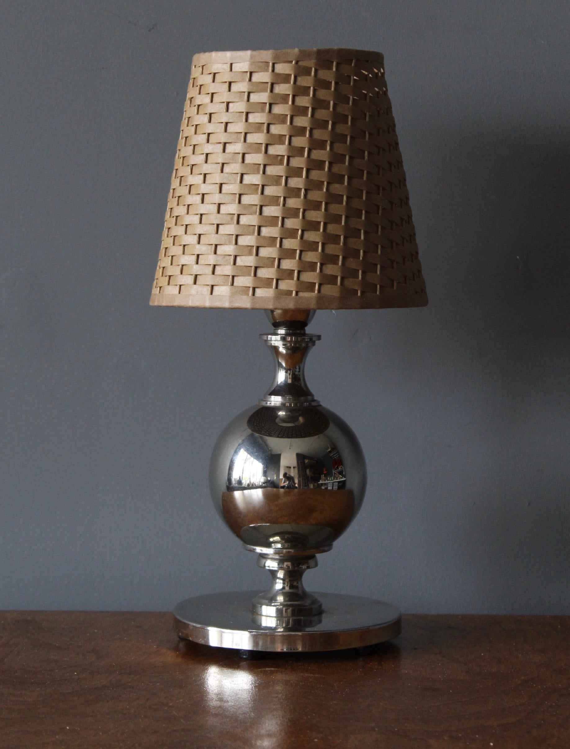 A table lamp, designed and produced in Sweden, c. 1940s. In polished chrome metal.

Stated dimensions include lampshade. Assorted vintage basket / rattan lampshade.