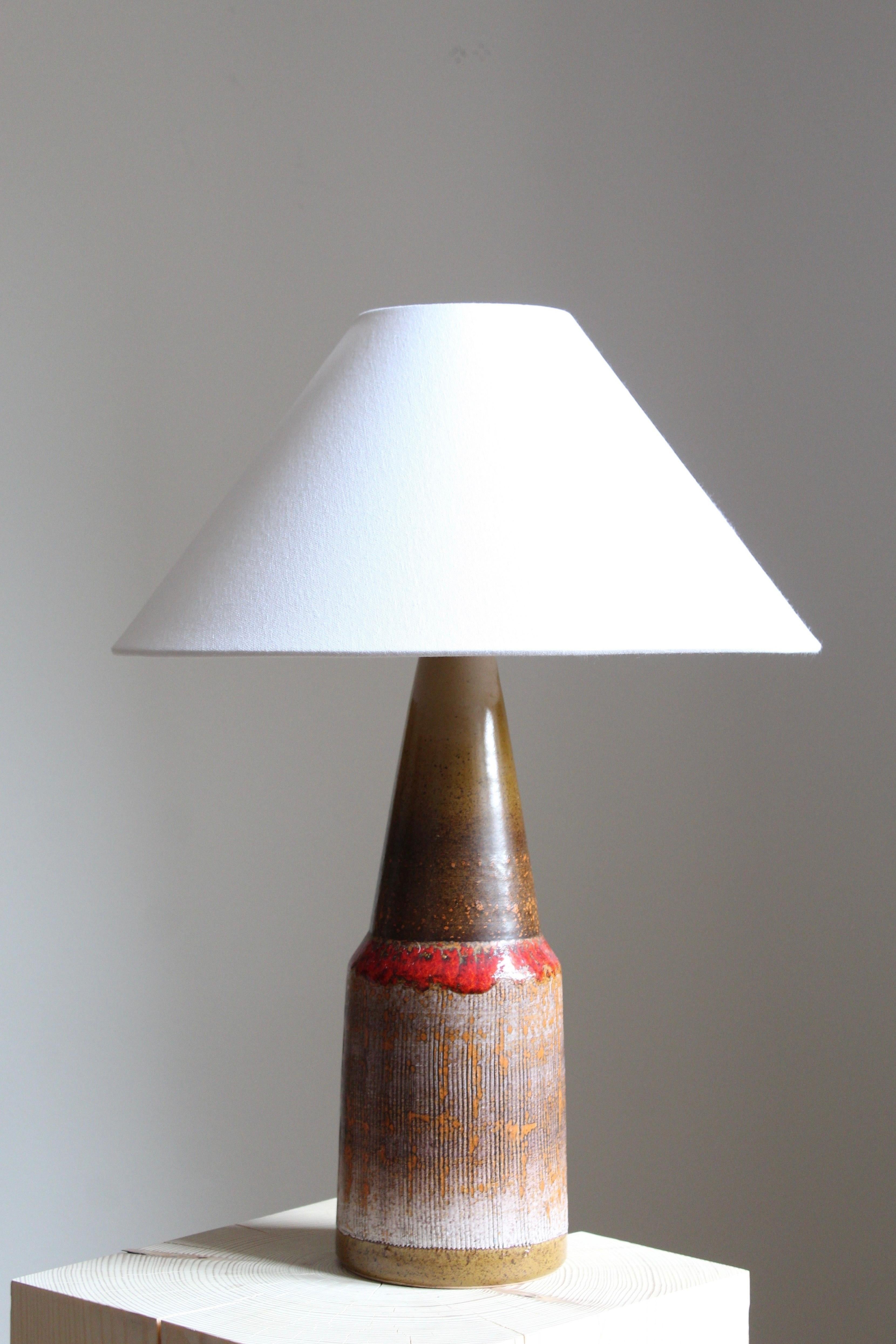 A sizable table lamp, stoneware with a highly artistic glaze. Lampshade not included.

Glaze features brown-orange colors with hints of white.