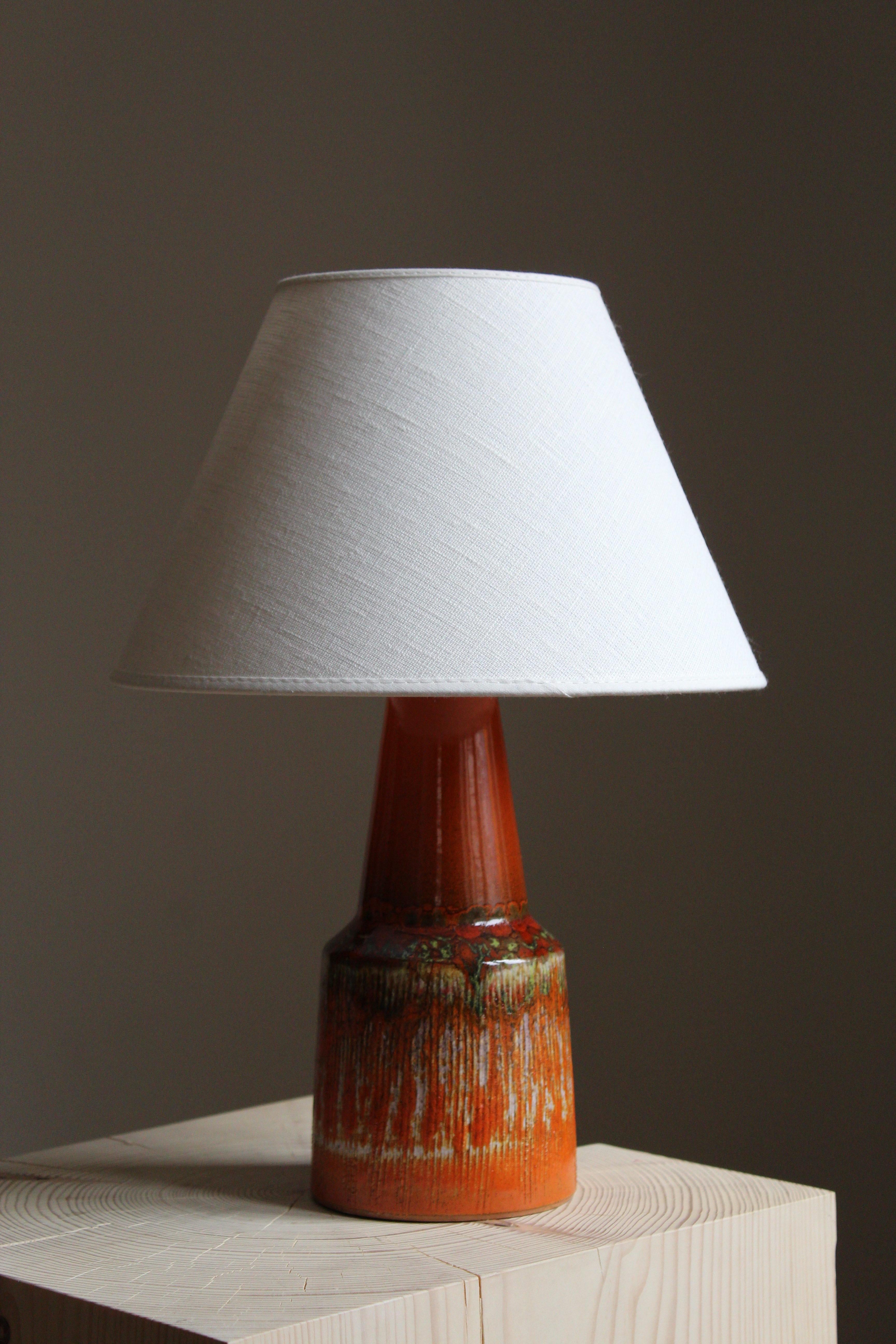 A table lamp, stoneware with a highly artistic glaze. Lampshade not included.

Glaze features orange-brown color and hints of green.