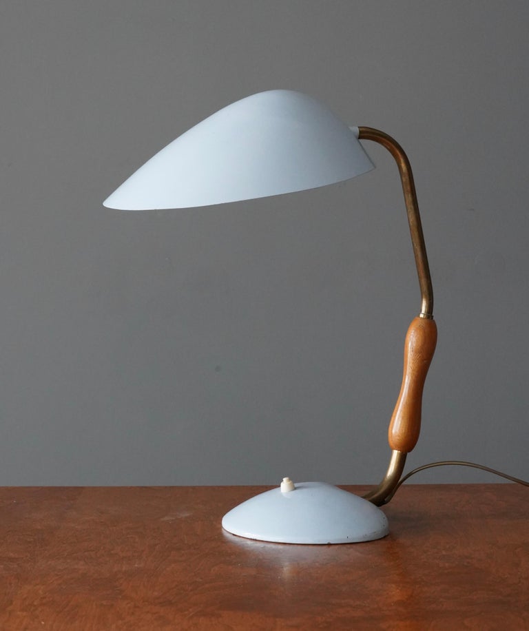 A an adjustable table lamp. In brass, lacquered metal, and with a teak grip. Produced in Sweden 1940s-1950s.

Other designers and makers of the period include Carl Axel Acking, Paavo Tynell, Alvar Aalto, Hans Bergström and Asea