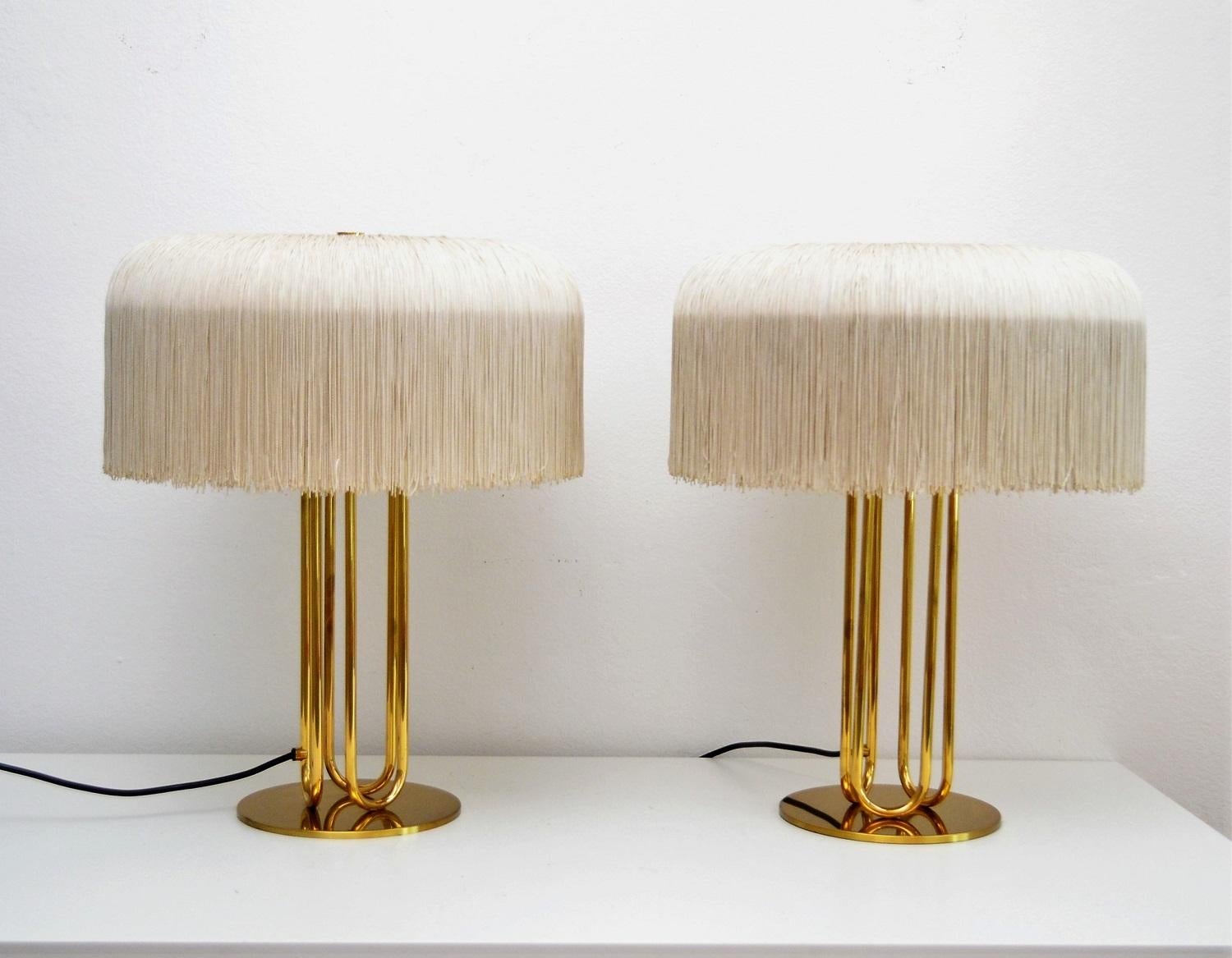 Magnificent elegant pair of big table lamps designed by Swedish Hans-Agne Jakobsson and manufactured during the 1960s.
The lamps bases are made of full heavy brass, whose golden color has taken a gorgeous dark patina.
The round lampshades are