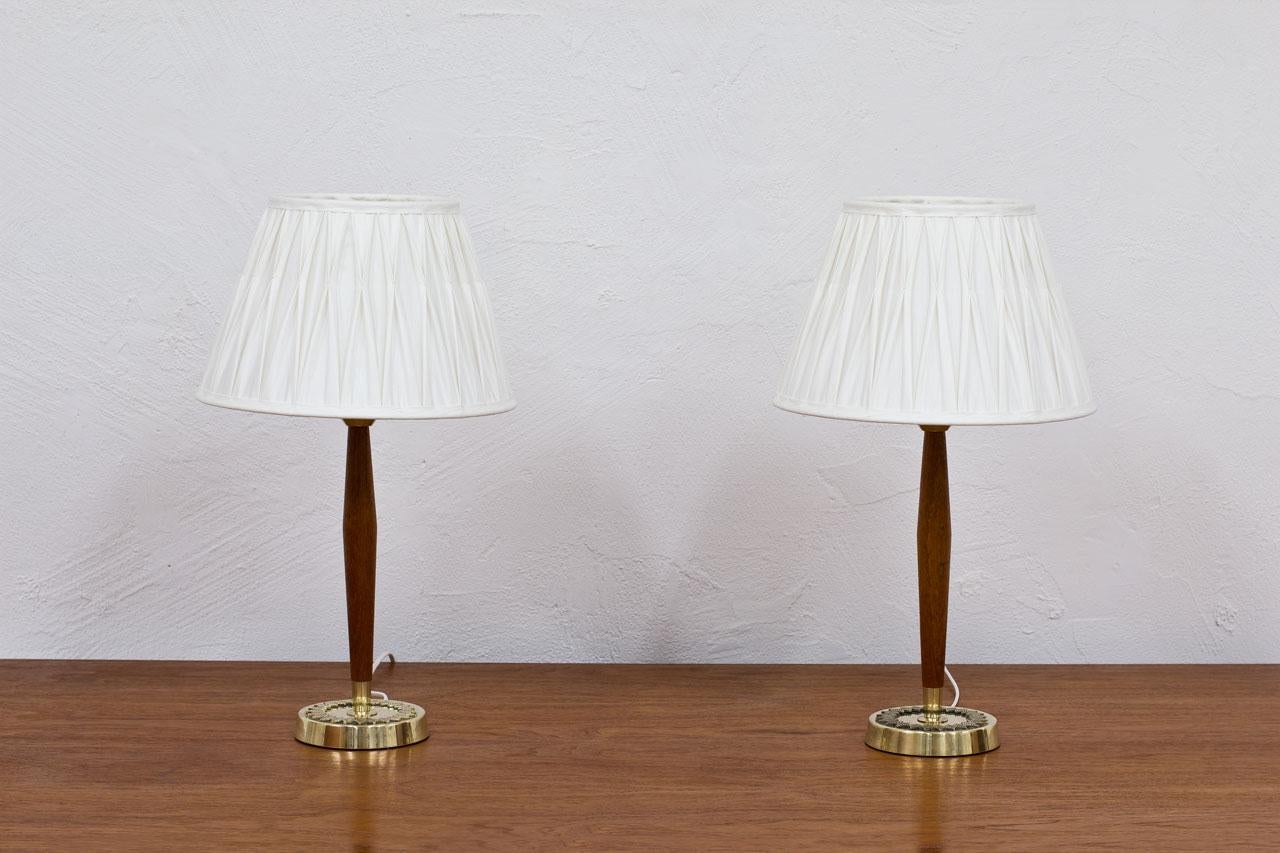 Pair of table lamps designed by Hans Bergström for ASEA. 
Manufactured in Sweden during the 1950s. 
Made from solid teak and polished brass. 
New wiring. New, hand sewn, off-white pleated chintz fabric shades.