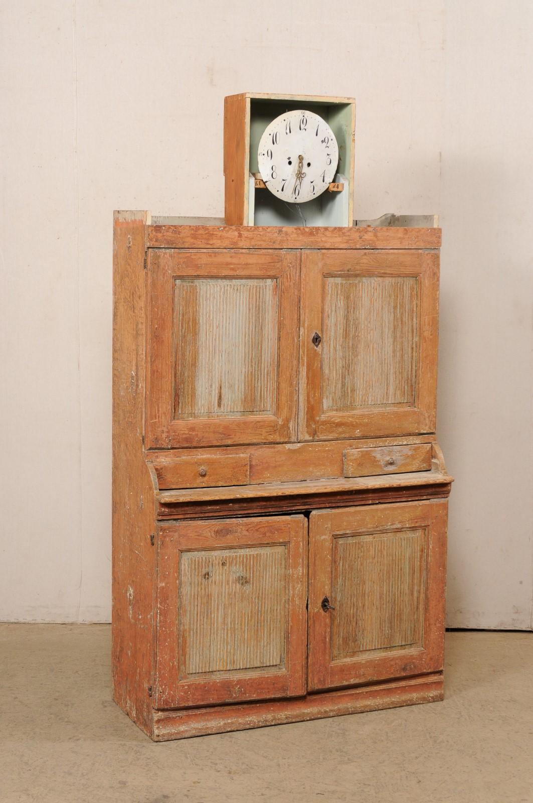 A Swedish Karl Johan period tall wooden clock cabinet from the early 19th century. This antique cabinet from Sweden, standing just shy of 7 feet in height, features an elegant swans-neck pediment style top, with clock set prominently within its