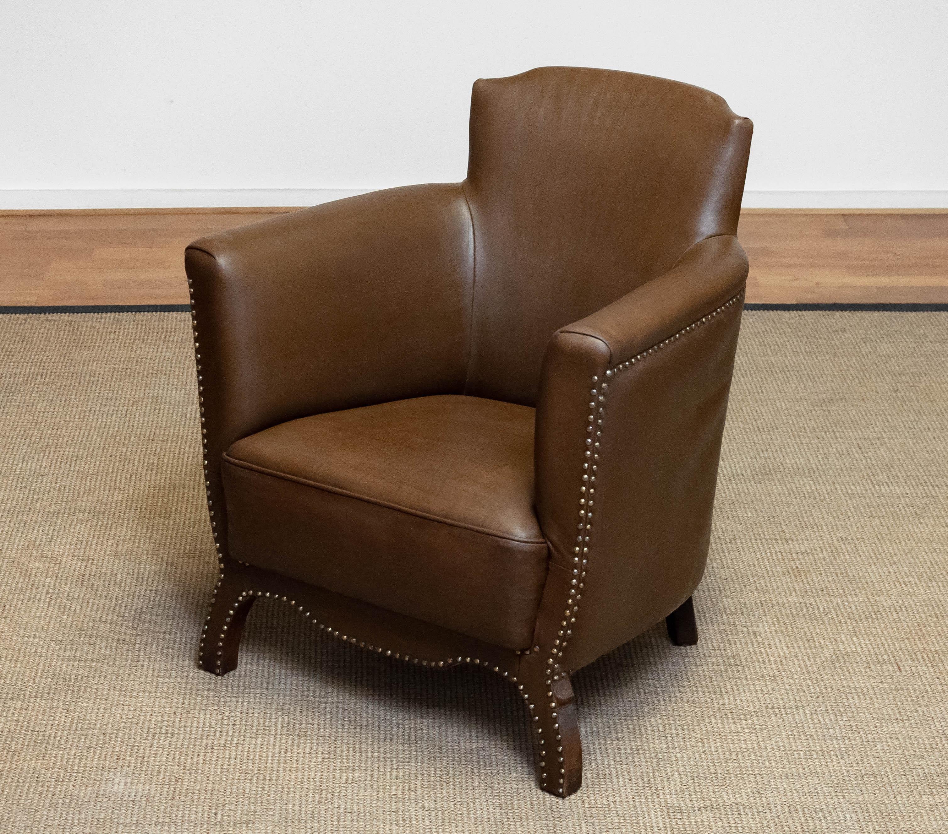 This 1940s Swedish Tan/Brown Nailed Leather Lounge Chair by Otto Schulz for Boet is a remarkable piece of early Scandinavian design. The chair features rich tan/brown leather upholstery, beautifully aged with a natural patina that highlights its