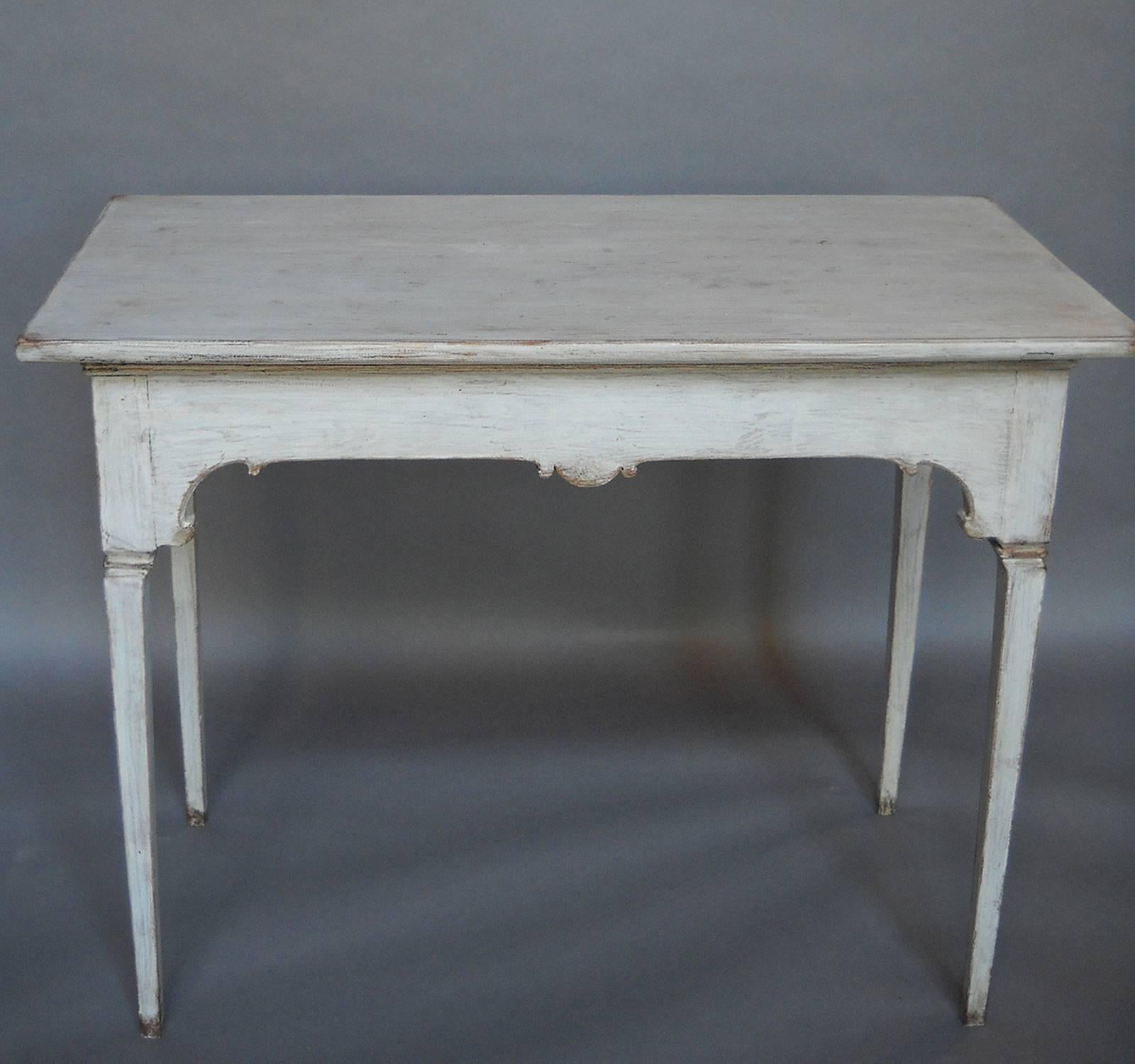 Gustavian period Rococo tea table, Sweden, circa 1790, with candle slides on either side. Shaped apron with square tapering legs. The top lifts away, leaving a tray table for serving.