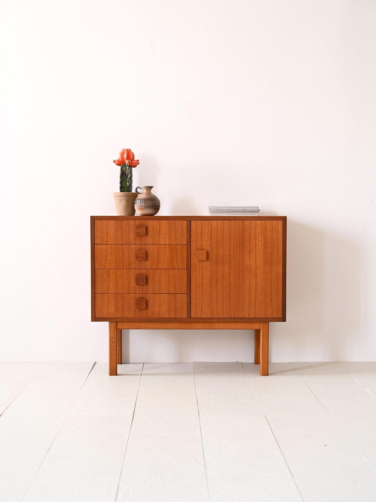Small Scandinavian sideboard from the 1960s.

A Scandinavian modernist piece of furniture whose storage space consists of a compartment with a hinged door on one side and 4 drawers on the other. Square-shaped wooden handles give it an original look