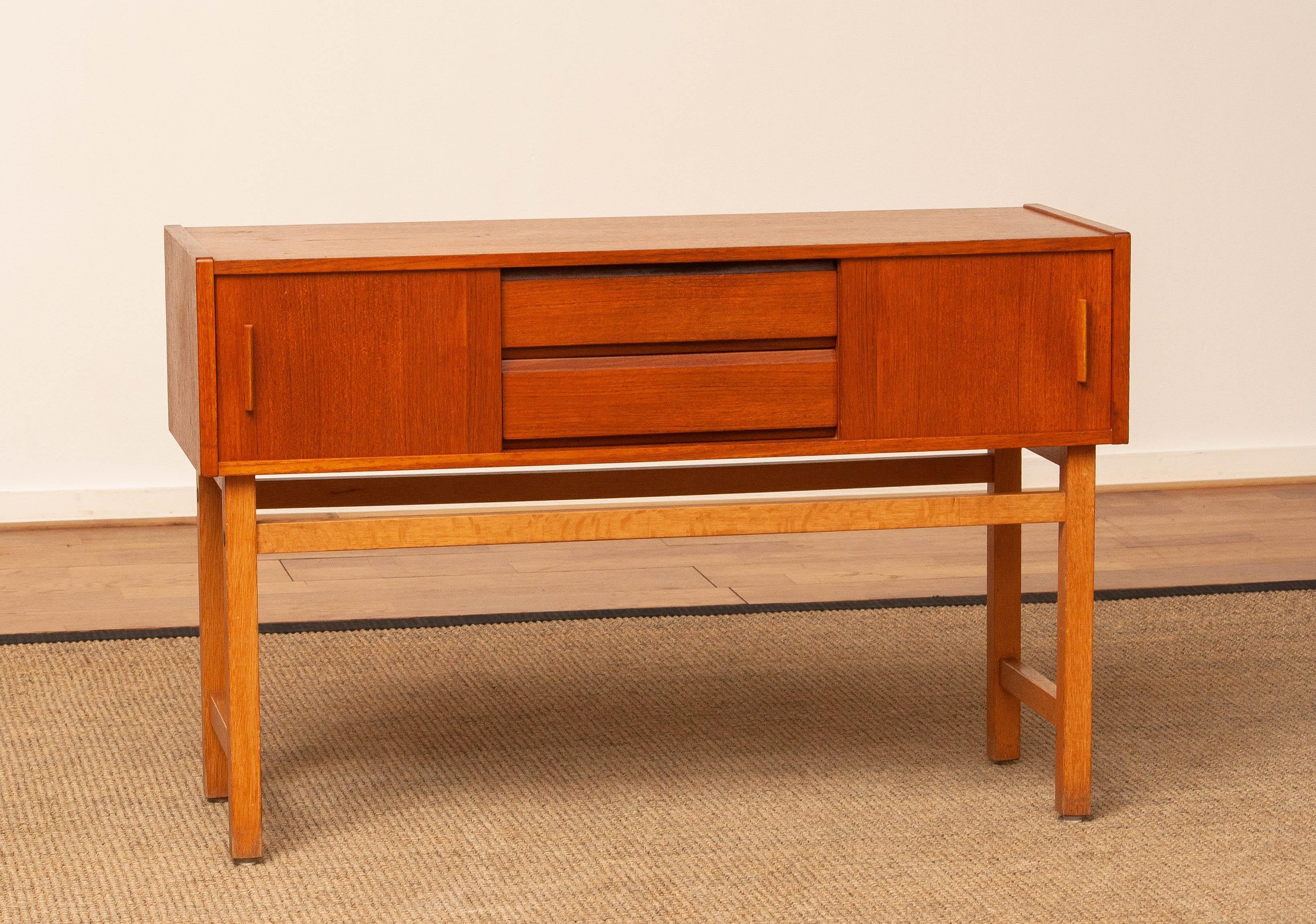Eleganza del mobile da corridoio in teak proveniente dalla Svezia, realizzato negli anni '60. Il mobile presenta un design equilibrato con due ante scorrevoli su entrambi i lati e due cassetti centrali, per offrire un'archiviazione versatile per gli