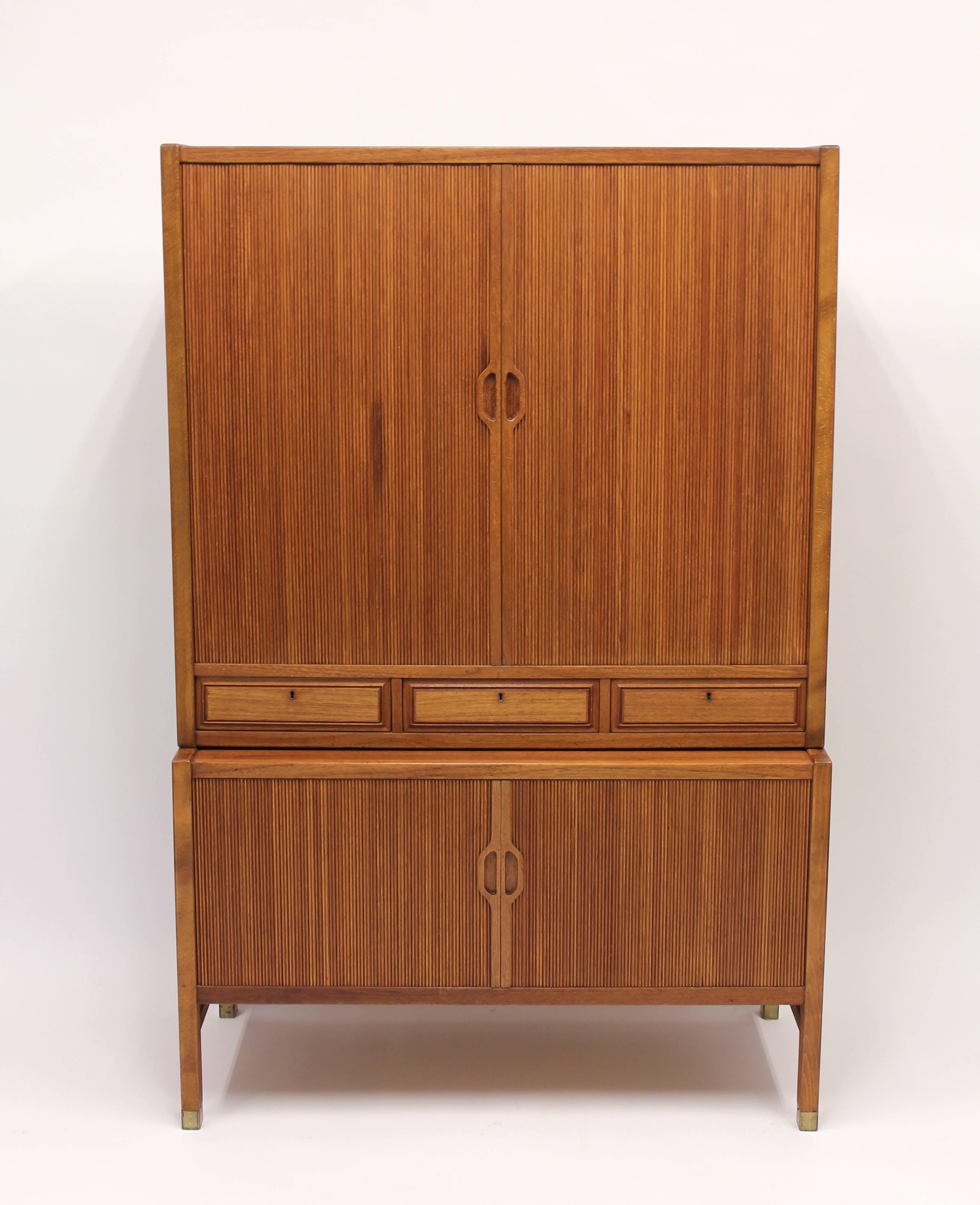 Swedish 1950s teak cabinet on brass feet with jalousie doors on both the top and bottom sections designed by Carl-Axel Acking for Bodafors. One of the inside drawers is stamped with the makers mark. It is in very good vintage condition.