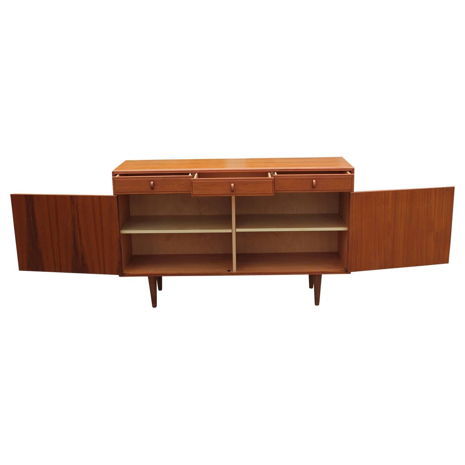 Teak sideboard by Swedish furniture company Bodafors. Was made in the 1960s and has three top drawers for storage with wooden, arch shaped handles. Also the piece has two large storage cabinets with wooden shelves and comes with a key.