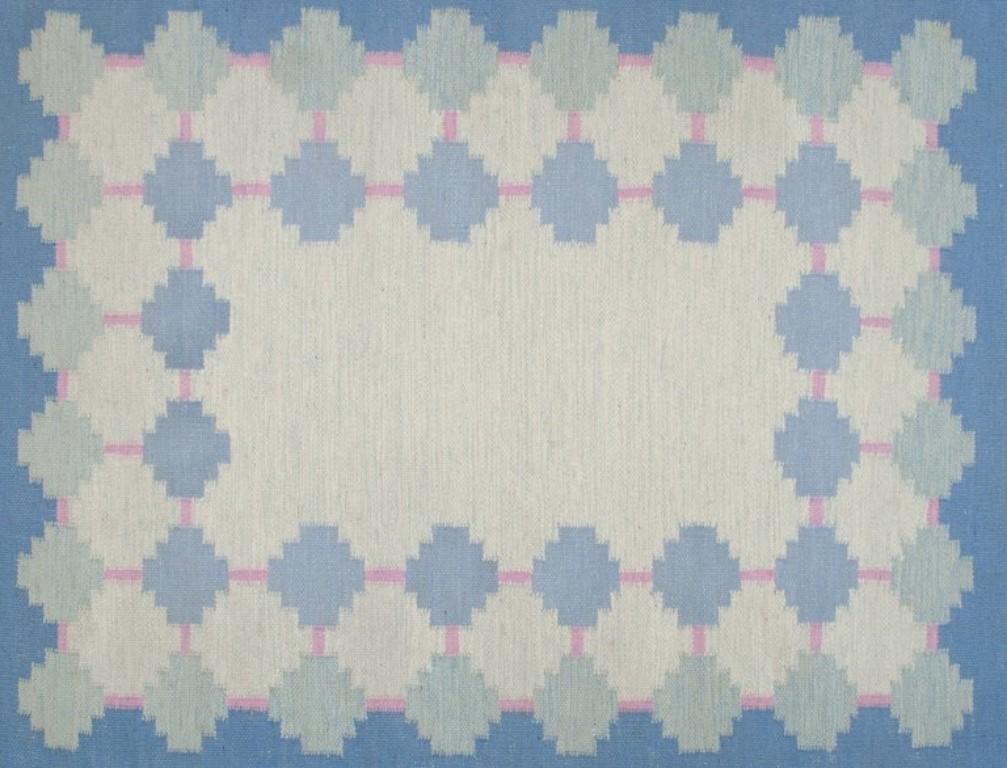Swedish textile artist. Handwoven wool carpet in Rölakan technique. 
Modernist design. Blue and pink colors in a geometric pattern.
Approximately 1970.
In good condition. Could benefit from cleaning.
Dimensions: 197 cm x 140 cm with fringes.