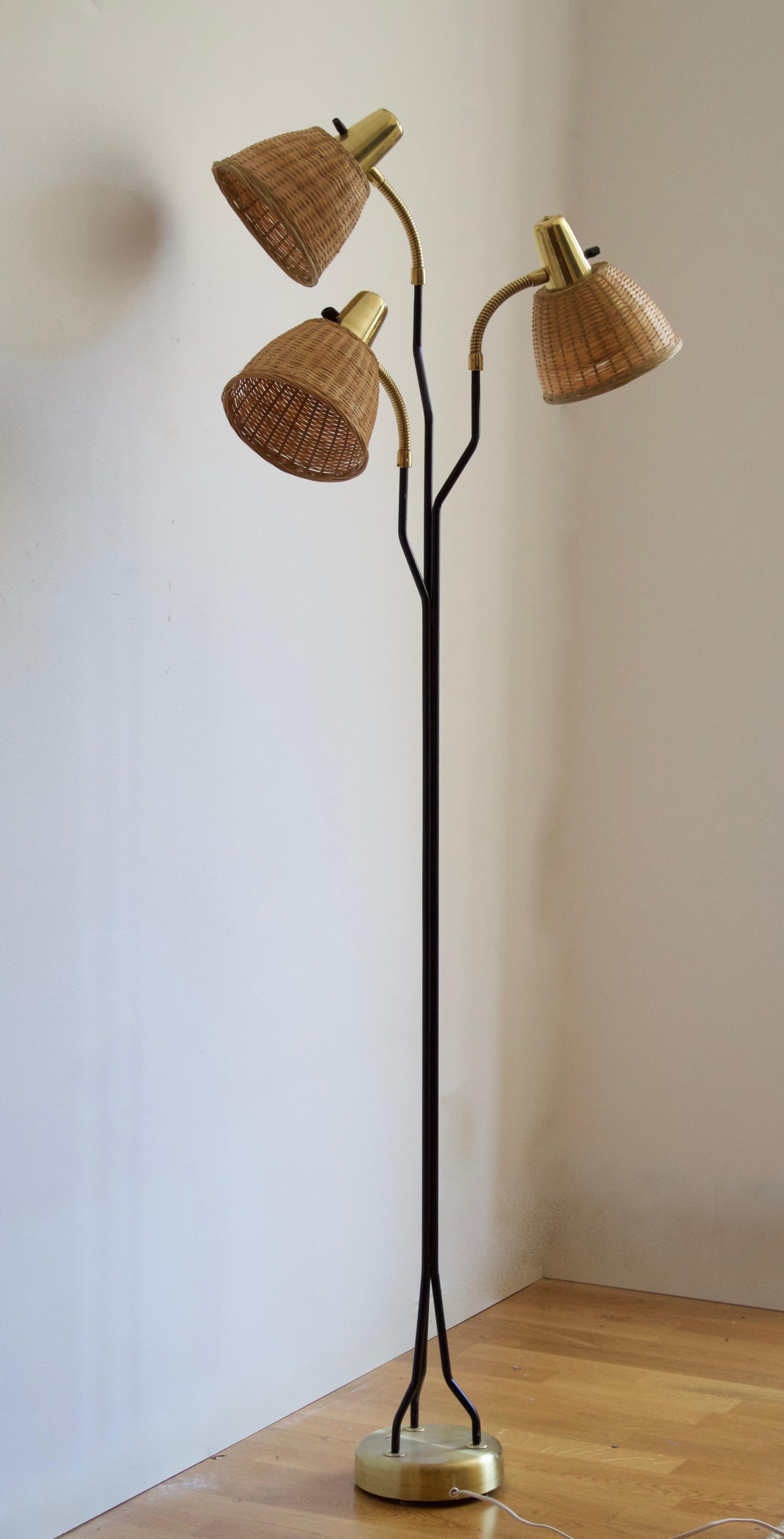 An adjustable three-armed floor lamp. In lacquered metal, brass. Assorted vintage rattan lampshades.