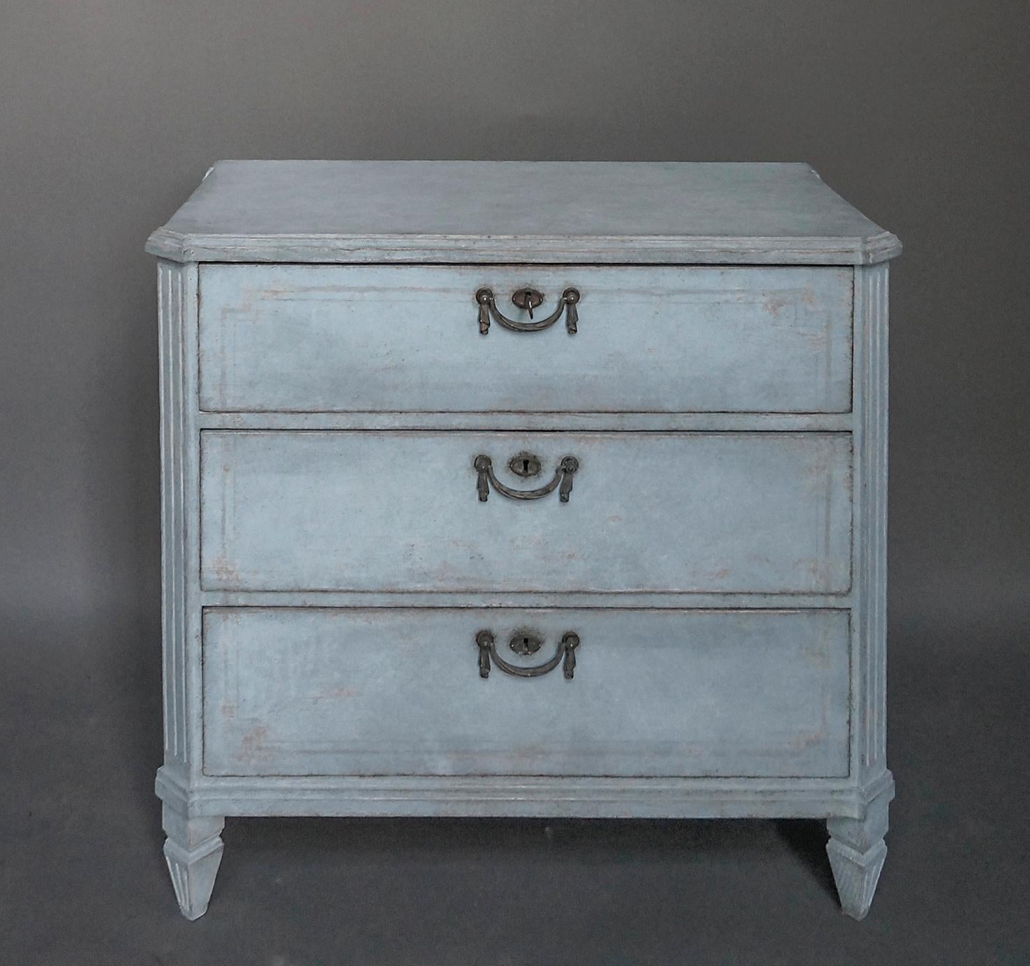Nice little three-drawer commode in soft blue paint, Sweden, circa 1880. Shaped top with canted corners, incised decoration on the drawer fronts, and period brass hardware.