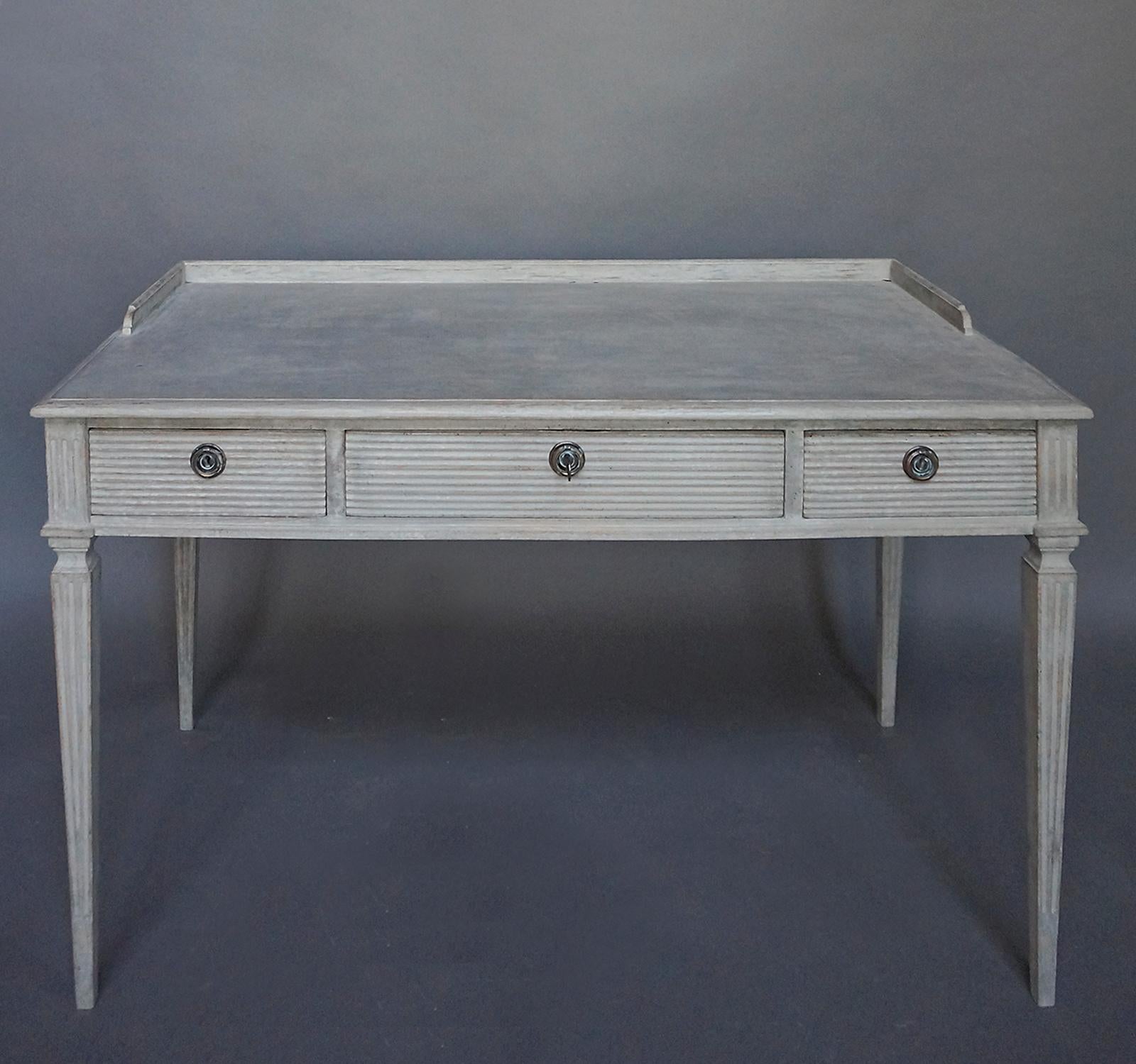 Wide writing or console table, Sweden, circa 1920, with three reeded apron drawers and a gallery top. Reeded and tapering square legs.  Original hardware.