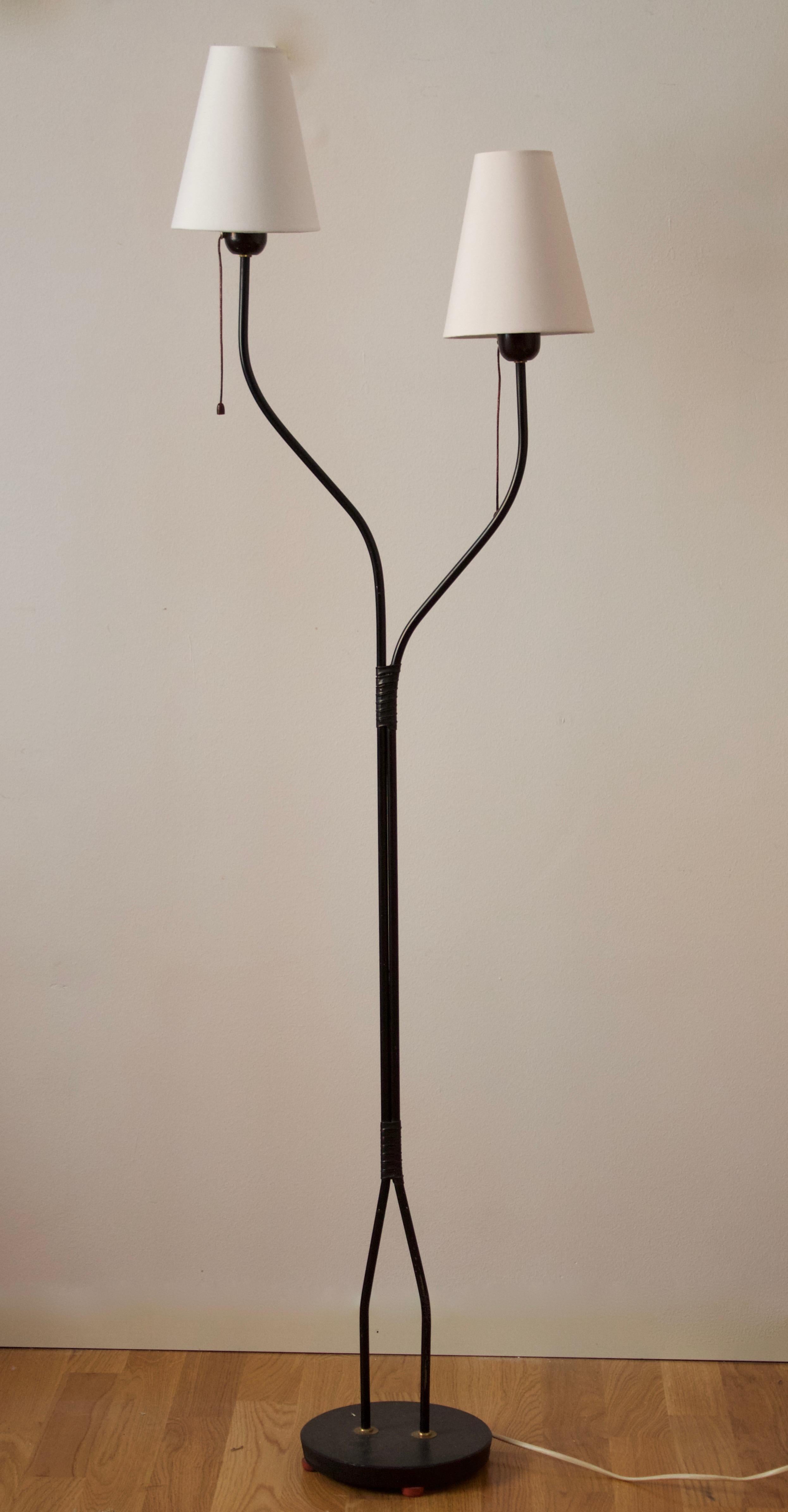 A two-armed floor lamp. In lacquered metal, acrylic. Brand new lampshades, Sweden, 1950s.