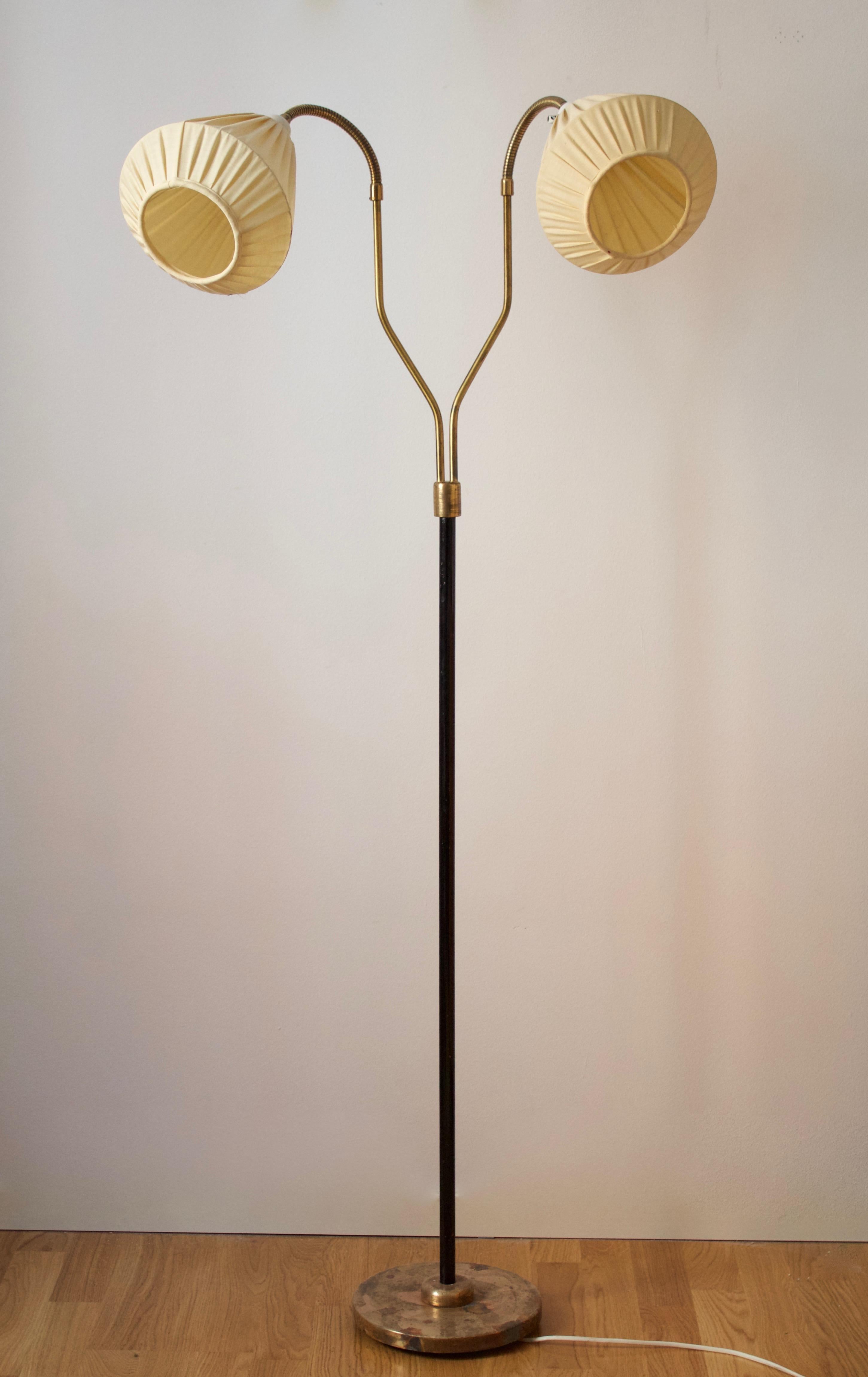 An adjustable two-armed floor lamp. In lacquered metal, brass, fabric. Vintage lampshades.