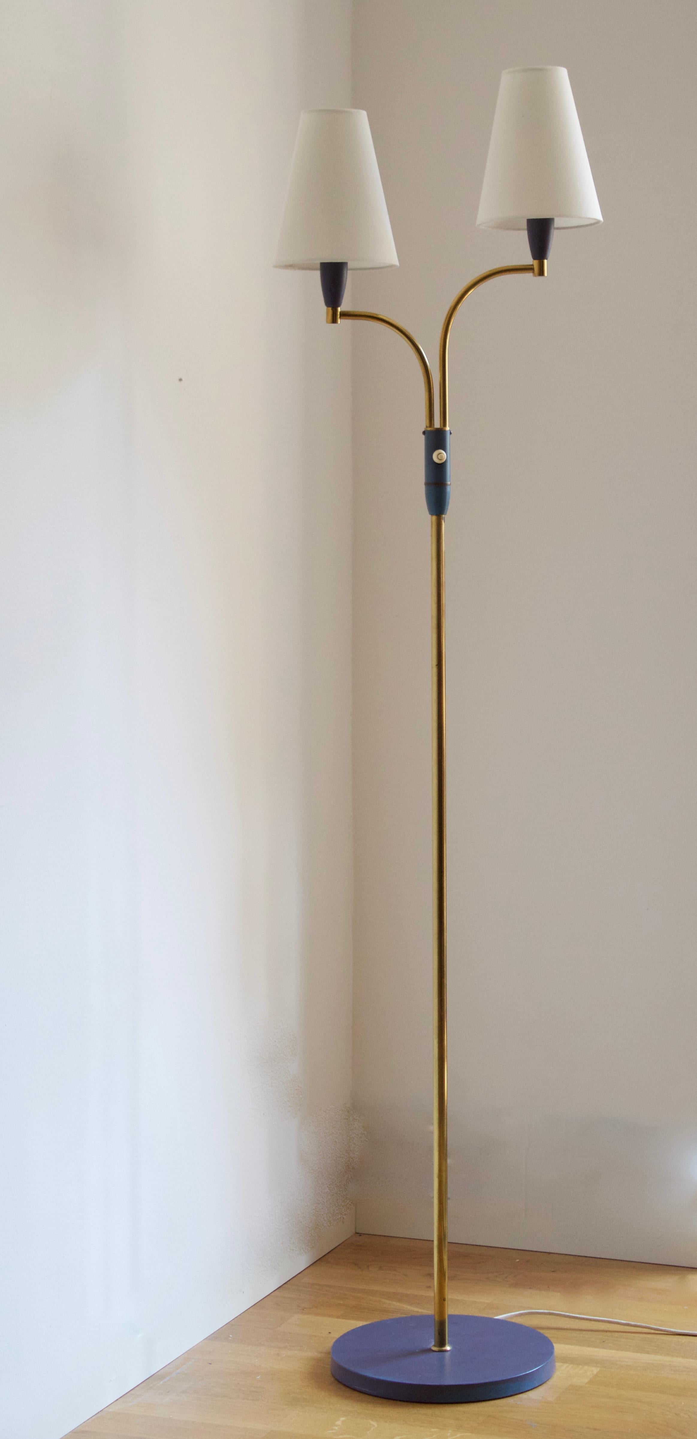 A two-armed floor lamp. In lacquered metal, brass. Brand new lampshades, Sweden, 1950s.