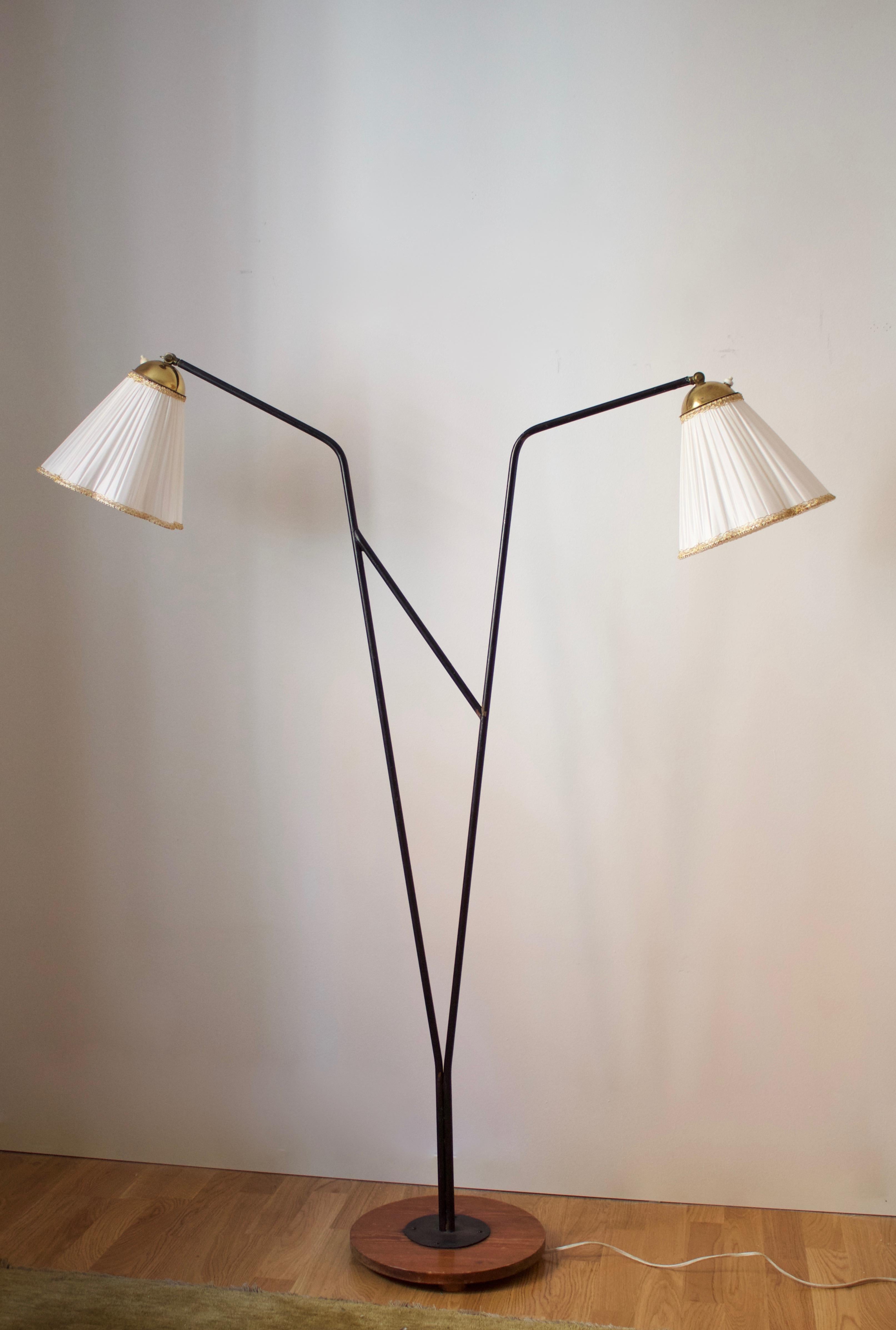 A two-armed floor lamp. In lacquered metal, brass, fabric, and wood. Brand new lampshades.