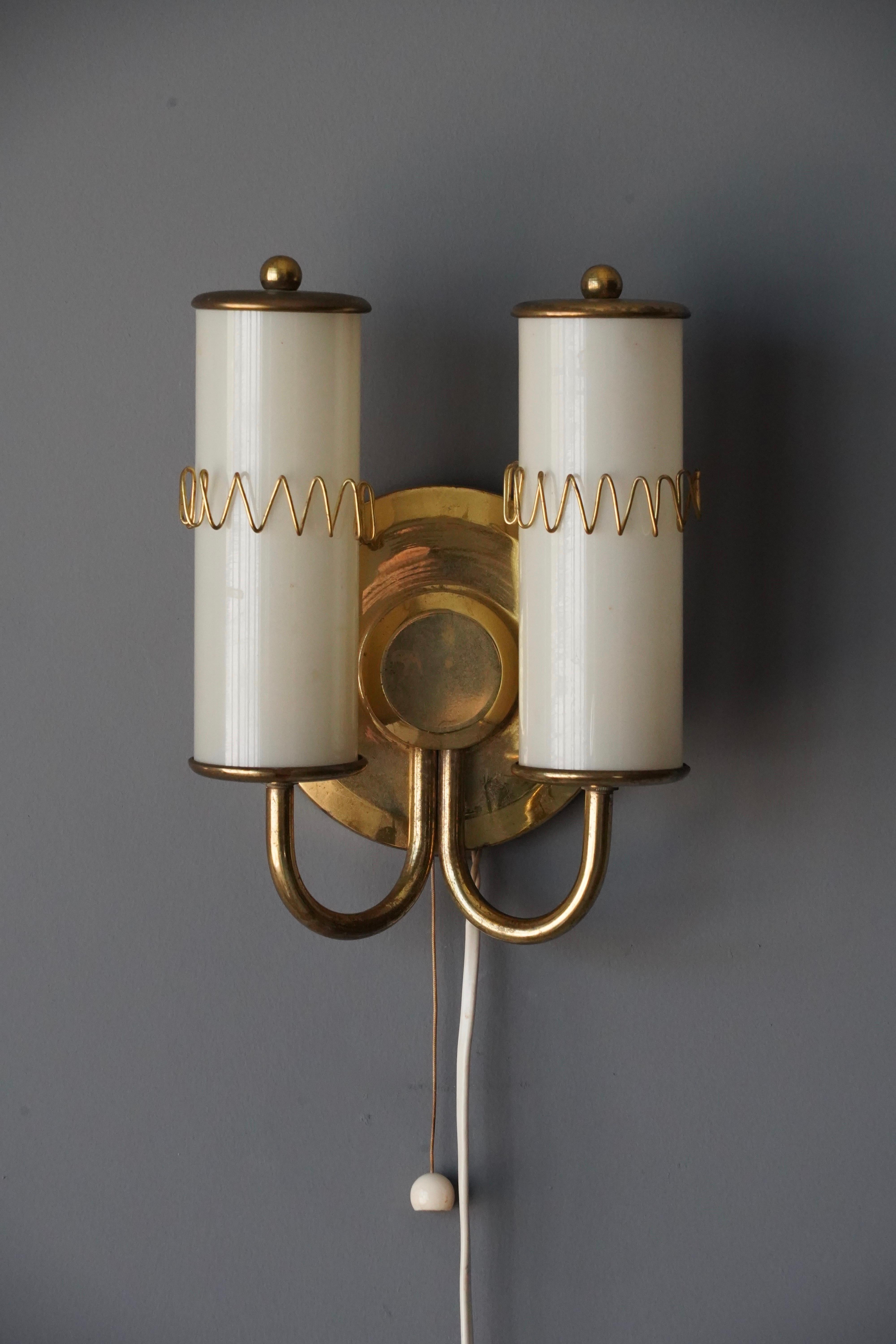 A wall light. Designed and produced in Sweden, c. 1940s-1950s. Features brass milk glass diffusers

Dimensions include shade. Shade is included in purchase. Configured for plug in. Please review wiring upon installation.

 