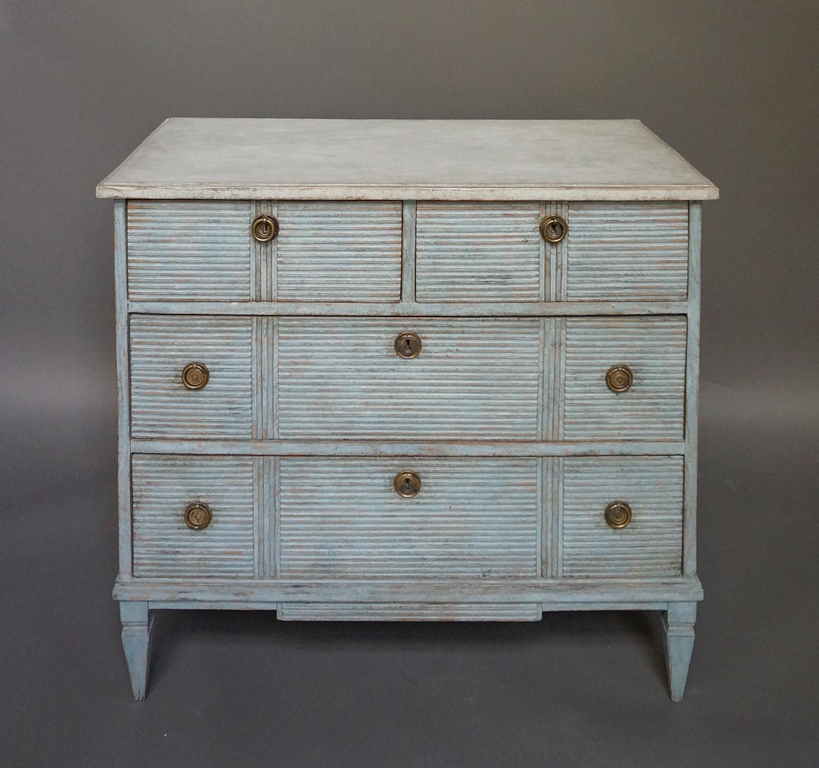 Swedish chest of drawers, circa 1860, with two half-width and two full width drawers over a shaped apron. The horizontal reeding on all drawer fronts is interrupted with bolder vertical lines. Tapering square legs; brass pulls.