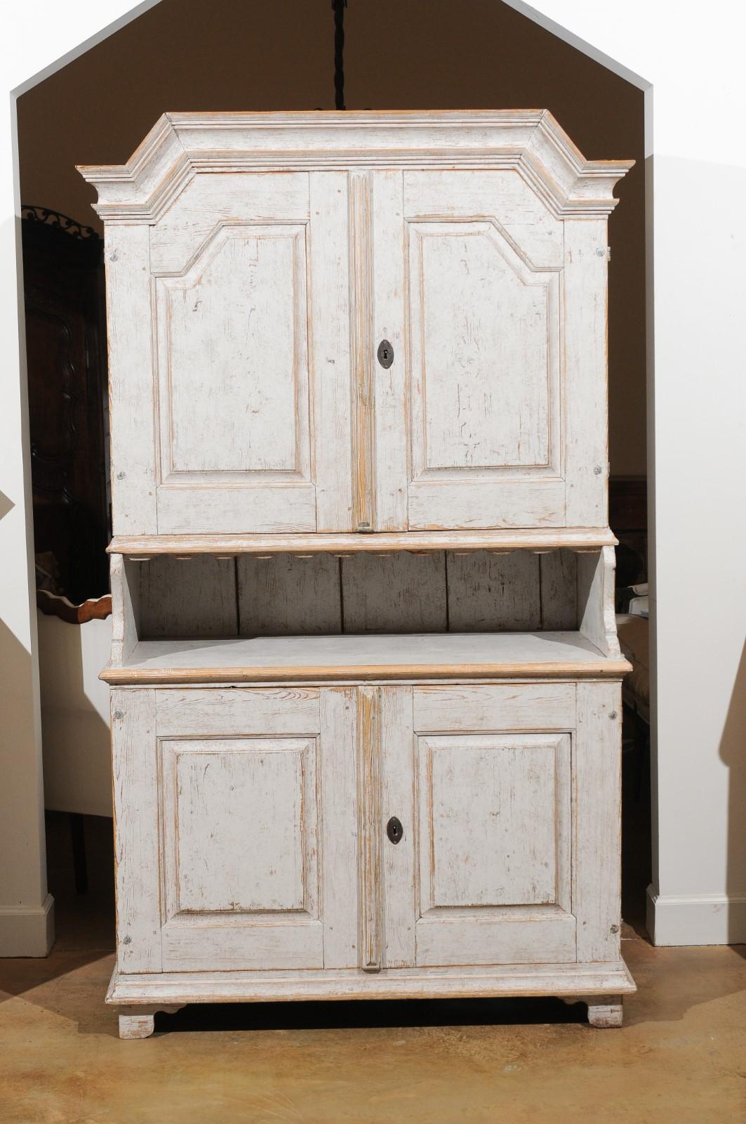 A Swedish mid-19th century two-part painted cabinet from the west-central province of Värmland, with broken pediment and four doors. Created in Sweden circa 1834, this tall painted two-part cabinet attracts our attention with its large broken