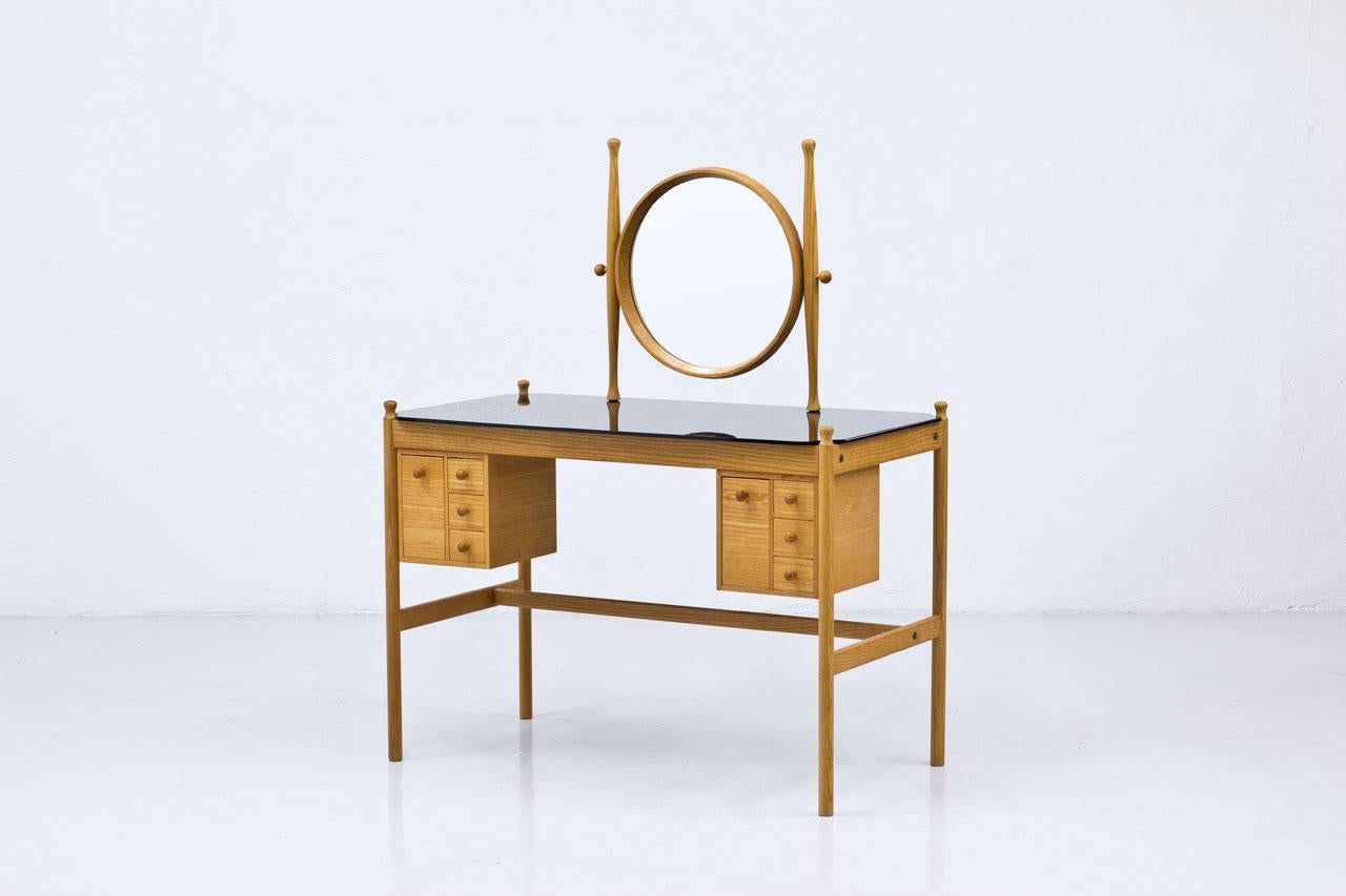Dressing table attributed to Fröseke AB Nybrofabriken, manufactured in Sweden during the 1960s. 
Made from oak with black glass top surface. Adjustable round mirror.