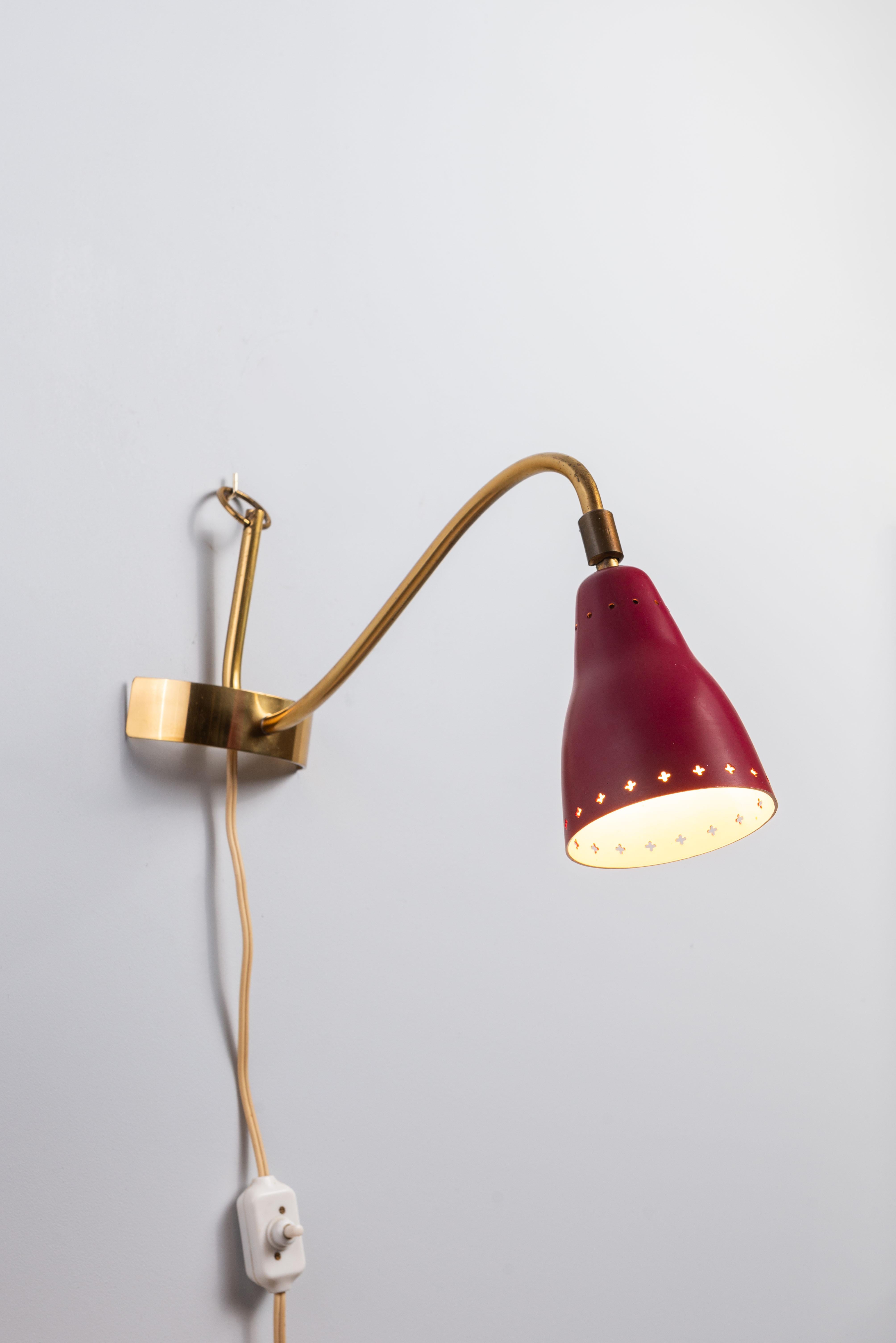 Lampe élégante en laiton et métal, polyvalente pour une utilisation à la fois comme lampe murale et lampe de table, par un designer inconnu, Suède 1950. Cette lampe est dotée d'un cadre élégant en laiton avec une courbure unique qui lui permet