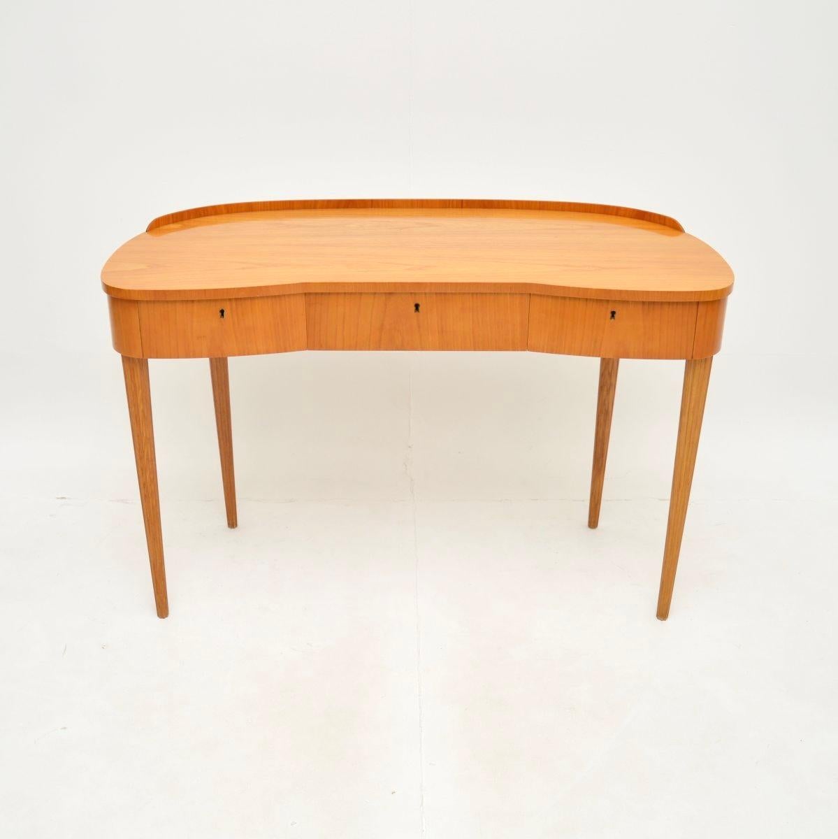 Un tocador/escritorio sueco vintage de olmo, elegante y muy bien hecho. Recientemente importado de Suecia, fue fabricado por Mobelbolaget y data de los años 50.

La calidad es fantástica, tiene un diseño precioso y se ve increíble desde todos los