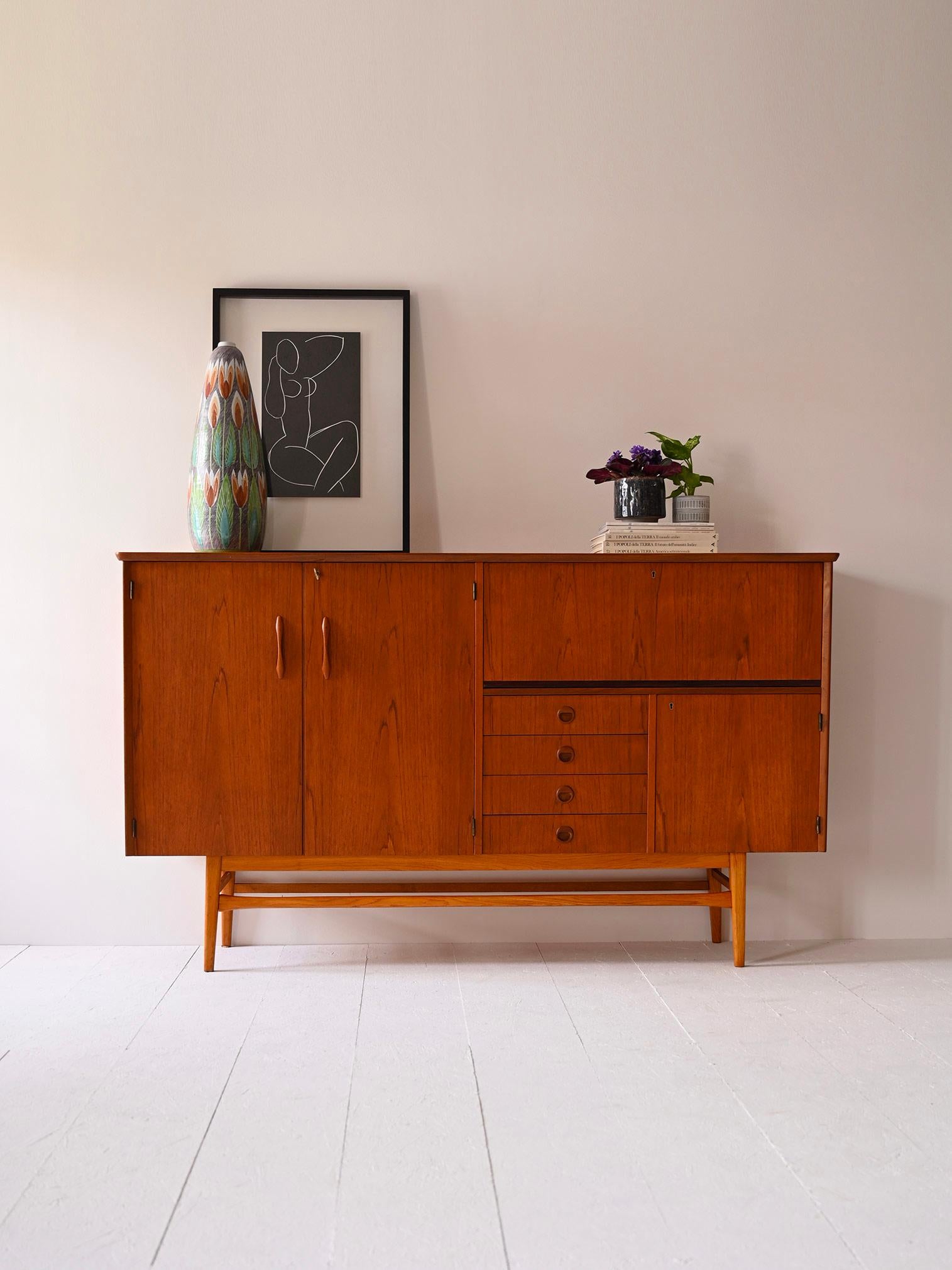 Original 1960s Scandinavian teak sideboard cabinet.

A piece of furniture with a modern flavor that traces the lines of mid-century design. Consisting of a compartment with hinged doors on one side and 4 drawers and two compartments on the other