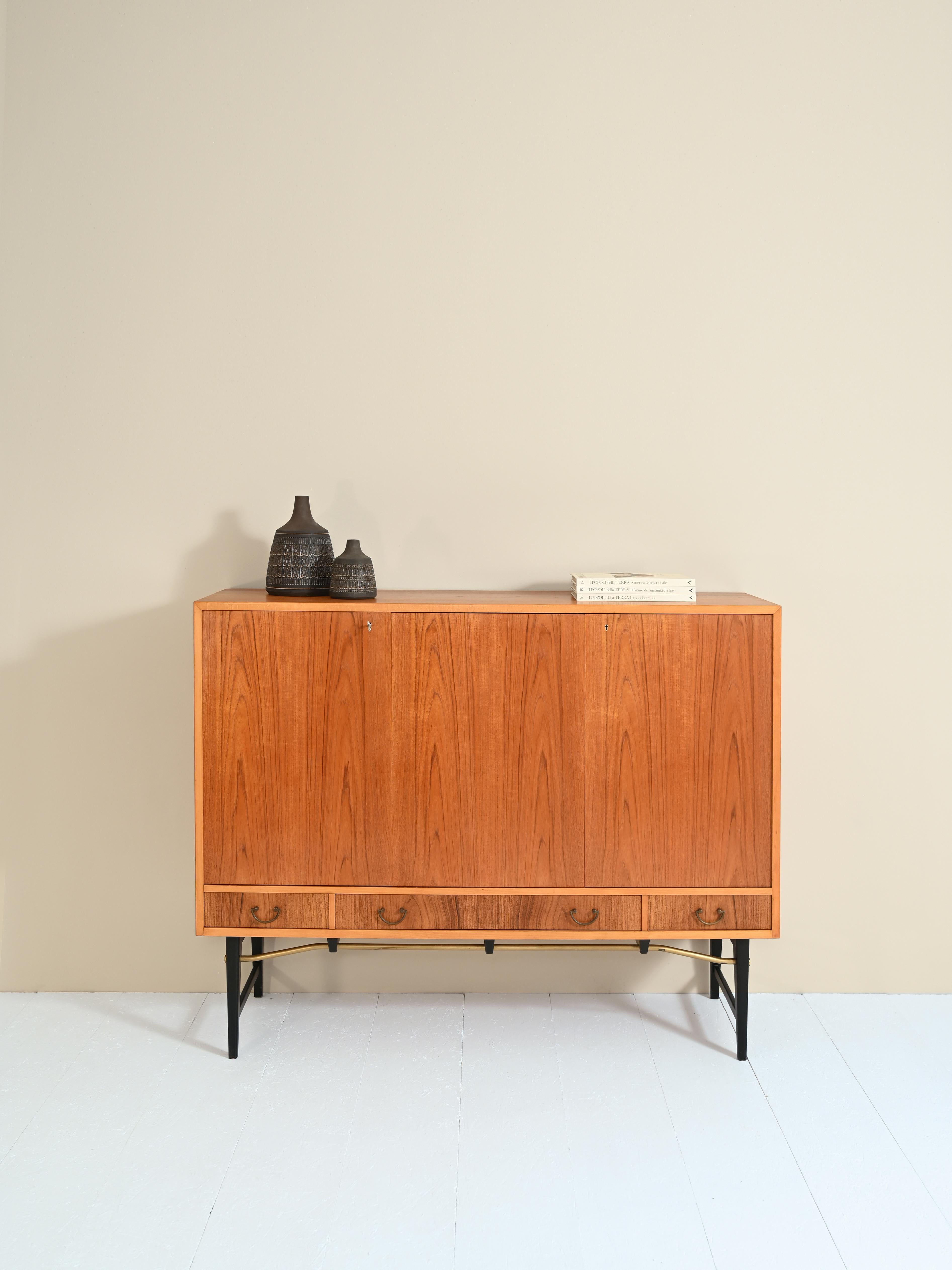 Teak sideboard with black painted feet.
The manufacture is Swedish original vintage.
Consists internally of two compartments with height-adjustable shelves.
Externally the cabinet is symmetrical due to the three hinged doors and four drawers with
